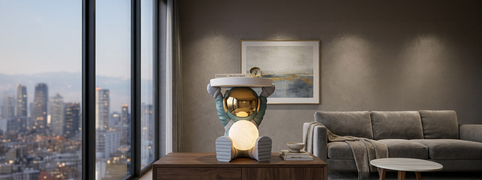 Astronaut sculpture with gold-mirrored visor and glowing moon lamp holding a round tray with a book and compass on a wooden console near city views.