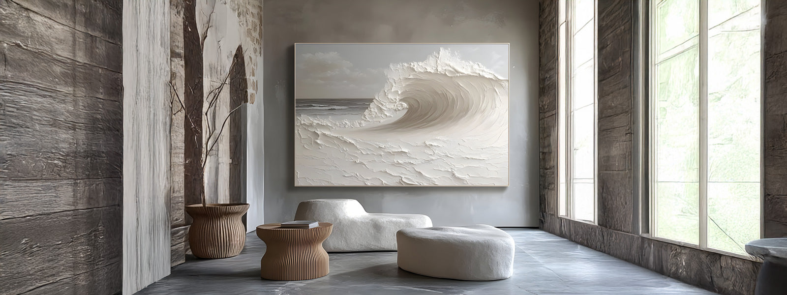 Large textured white wave painting on a pale wall in a minimalist room with stone columns, organic white seating, a wooden side table, and tall windows.
