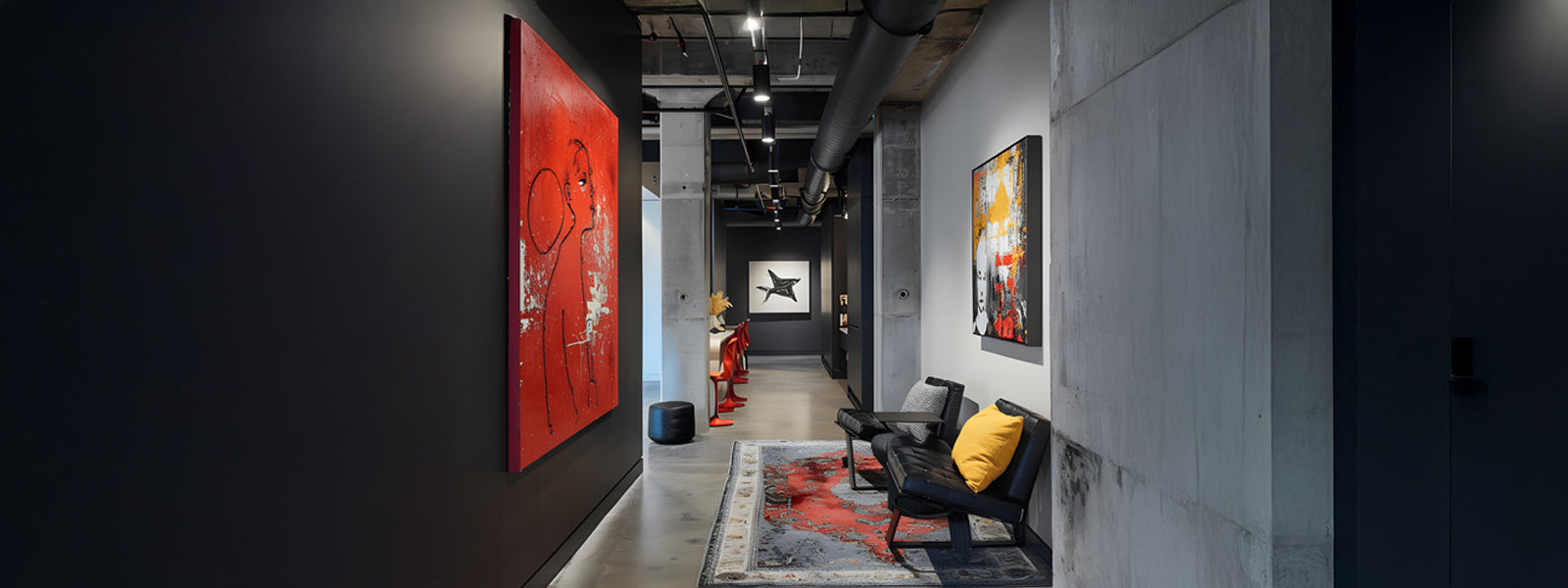 Industrial gallery hallway with a large red abstract painting, colorful wall art, sculptural figures, dark chairs with a yellow cushion, and a patterned rug.