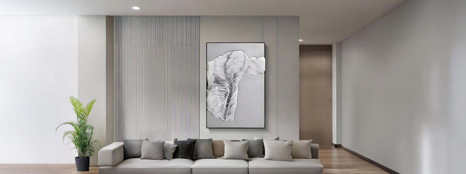 Large framed white textile art with flowing wave-like fibrous texture on a fluted grey wall above a low grey sofa in a minimalist living room.