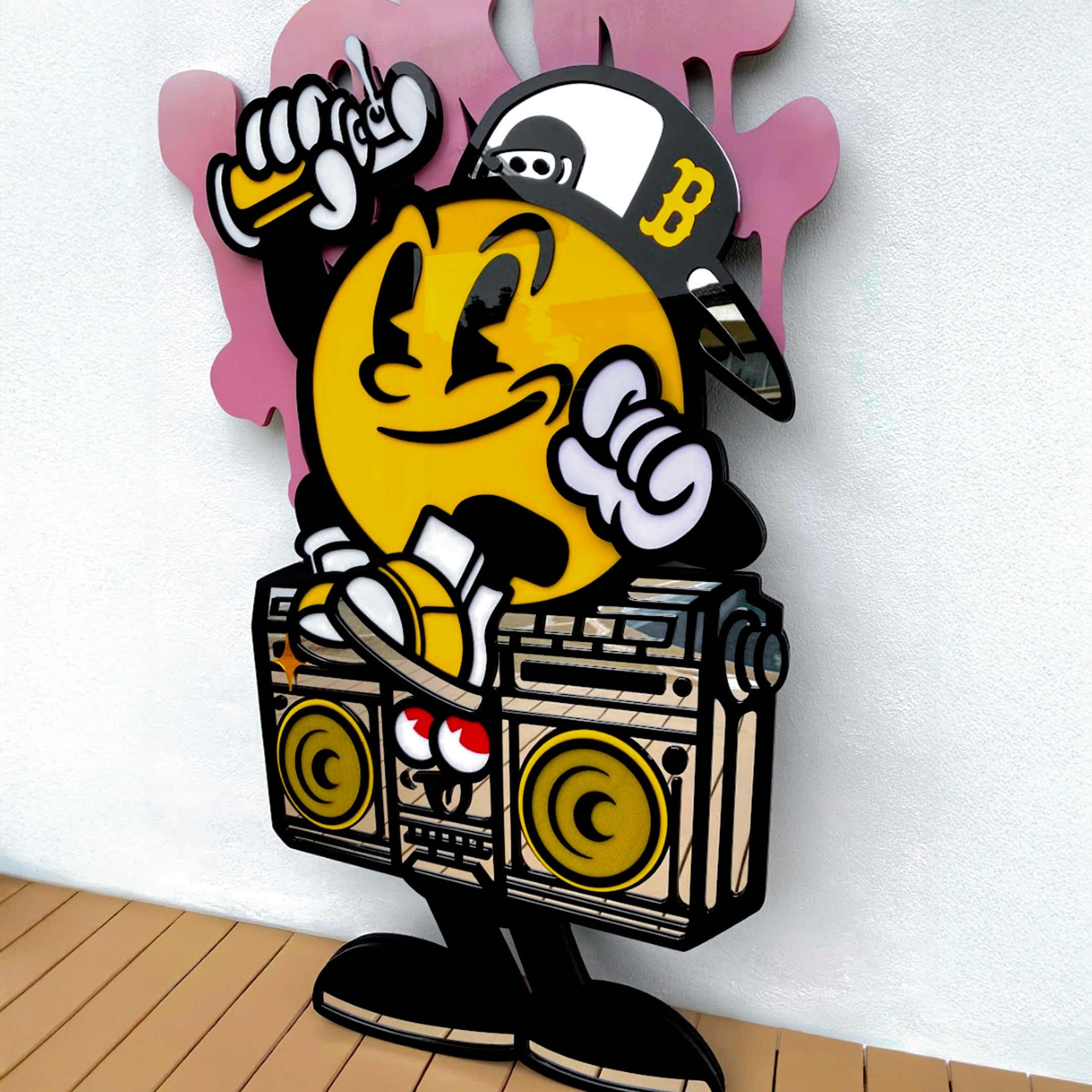 The Spray Your Love 3D Wall Art by Giant Sculptures features a cartoon-style yellow character in a cap, smiling and holding spray paint, with one foot on a boombox, set against pink graffiti shapes for bold street style.