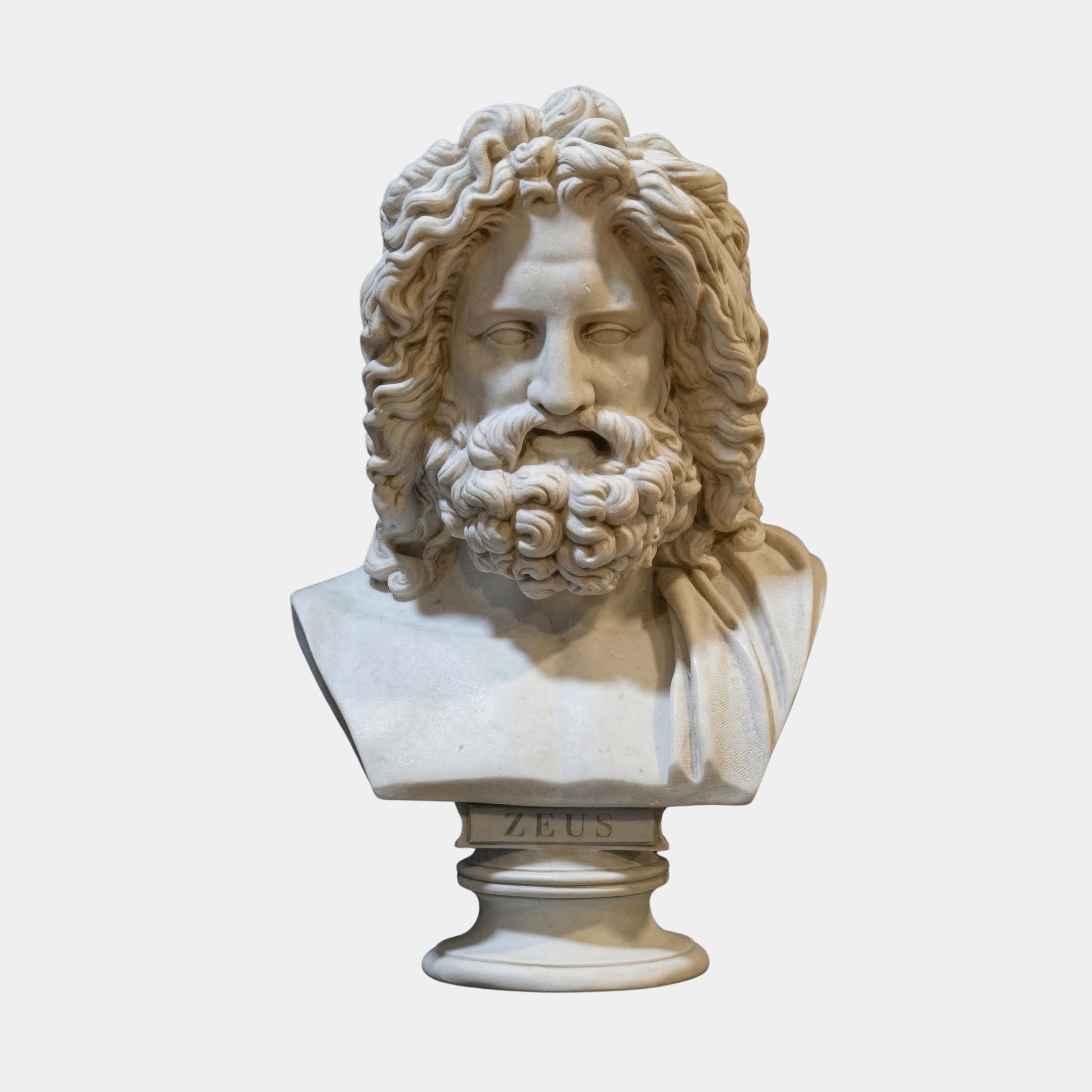 The Zeus Marble Bust Sculpture - 55cm by Giant Sculptures features a bearded man with long, curly hair and a draped robe. The base is inscribed with ZEUS, identifying this marble piece as the ancient Greek god.