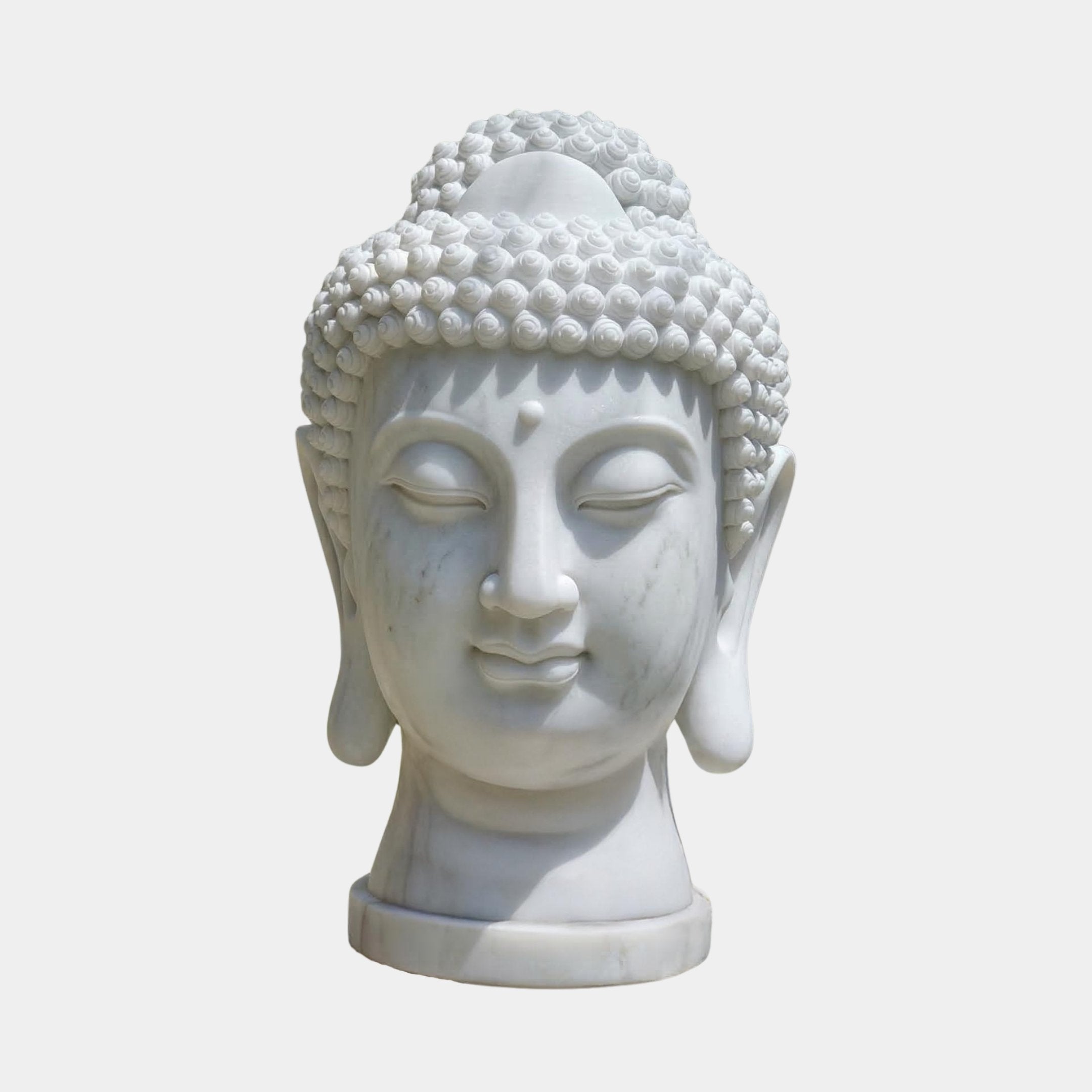 The Buddha Head Marble Sculpture - 50cm by Giant Sculptures features closed eyes, elongated earlobes, and detailed curls in white marble, evoking calm and serenity against a simple light backdrop.