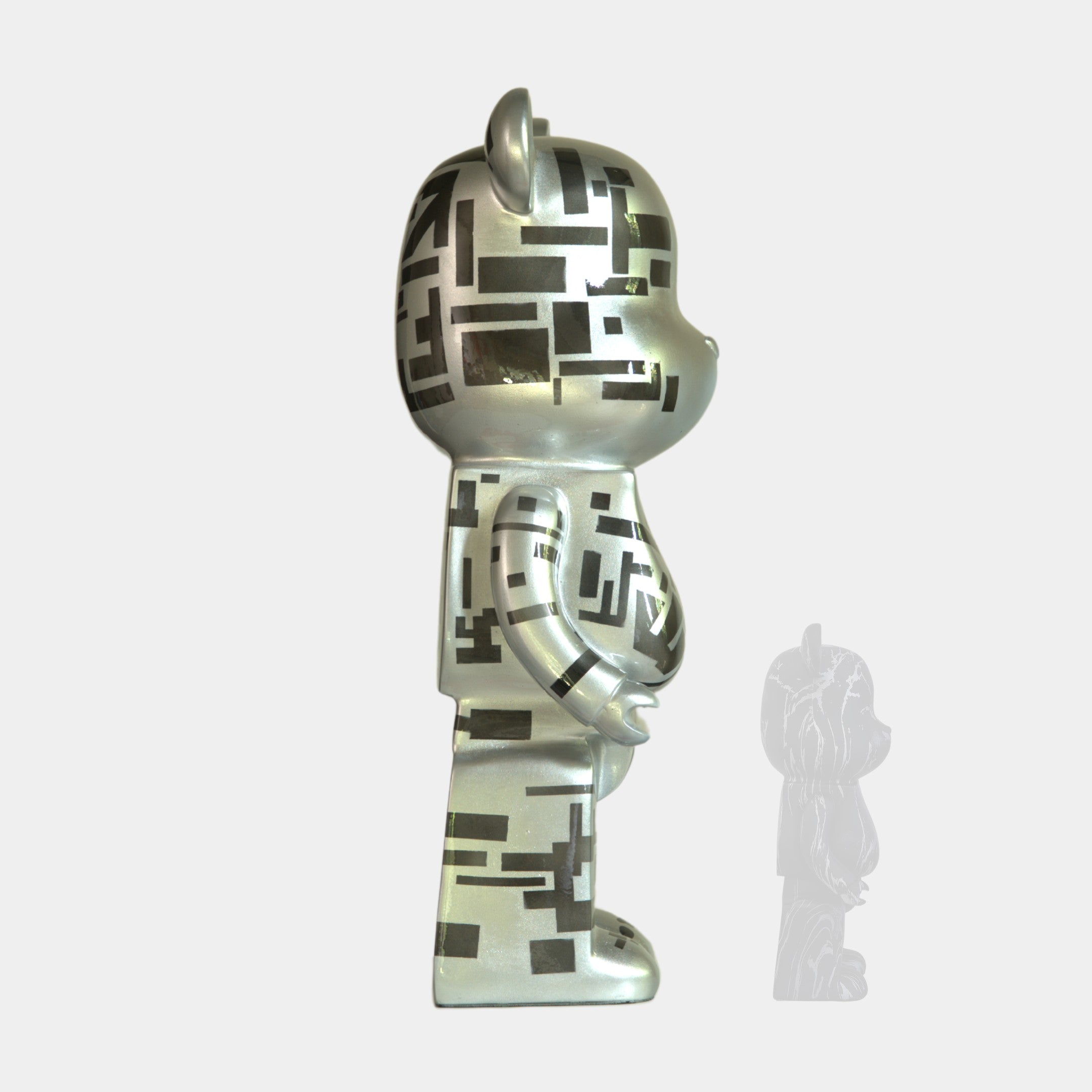 The Giant Sculptures Inside Appears Outside 3 Bear Sculpture (50cm) features a silver, mirror-like bear with black geometric patterns, standing upright and facing right, its semi-transparent shadow cast on a light gray background.