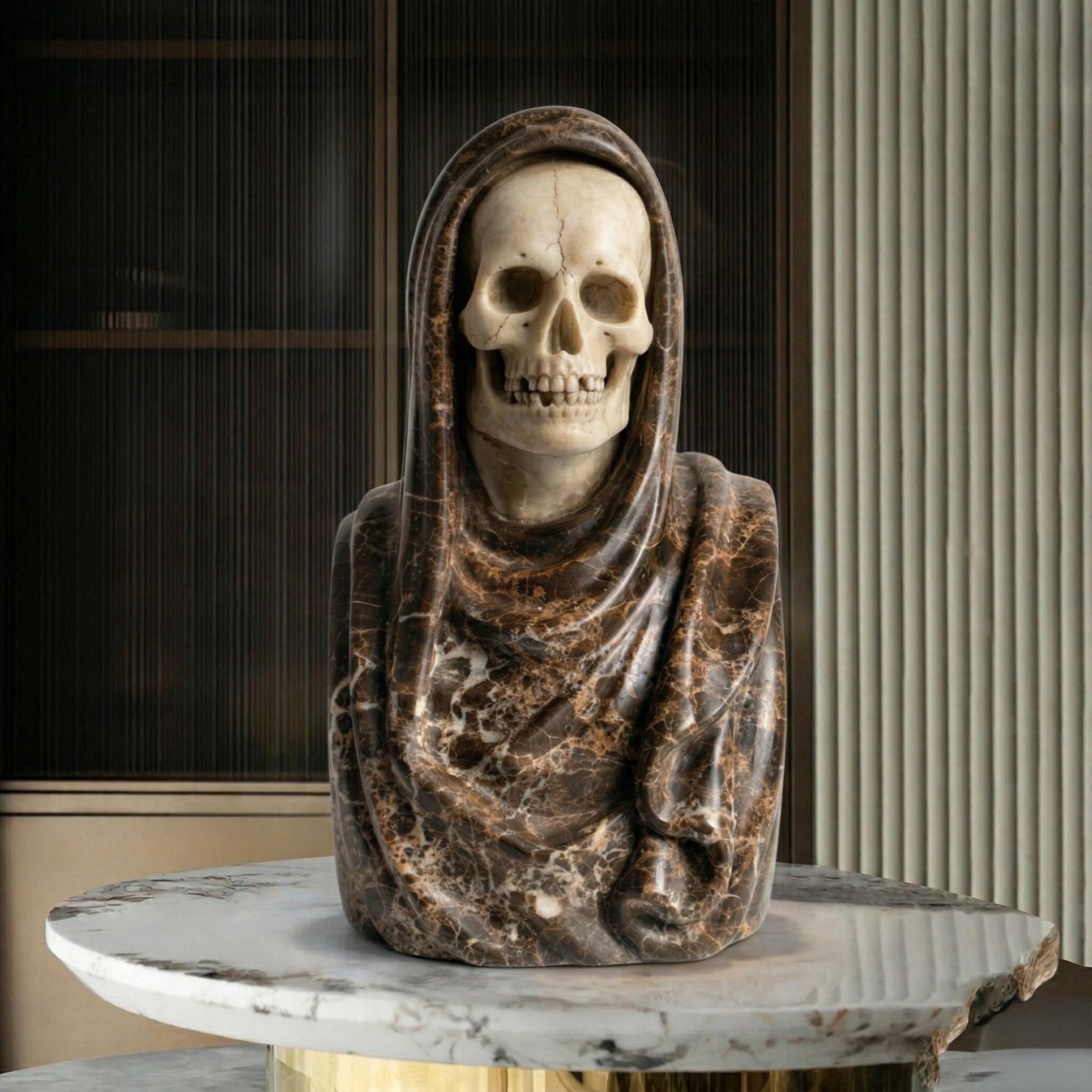 The Giant Sculptures Memento Mori Skull Marble Bust Sculpture (55cm) features a hooded skeleton design, displayed on a round marble table with striped and paneled walls in the background.