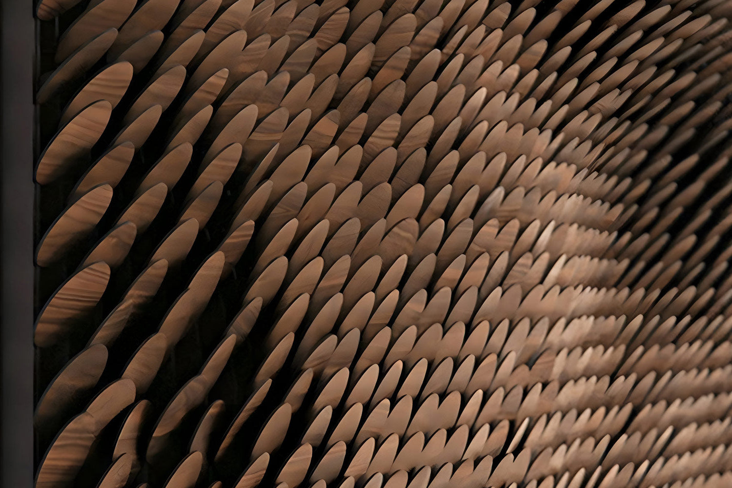 A close-up of an abstract wall installation featuring rows of overlapping, paddle-shaped wooden elements arranged in a wave-like pattern, creating a sense of depth and movement.