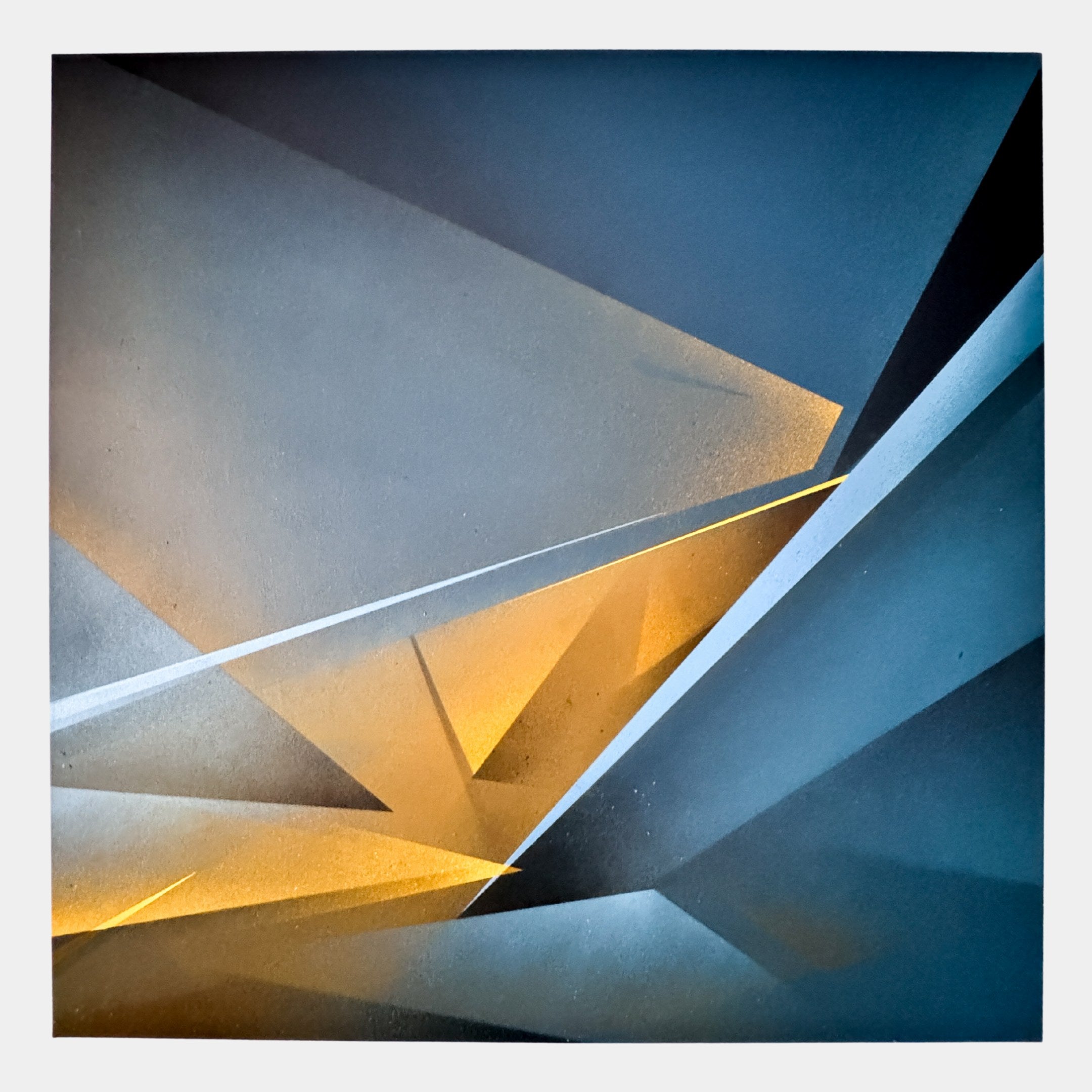 Skull&Stone I Abstract Canvas Wall Art by Giant Sculptures showcases sharp, overlapping blue and gray shapes with a warm yellow-orange center. This limited edition piece brings striking depth and contrast to any modern space.