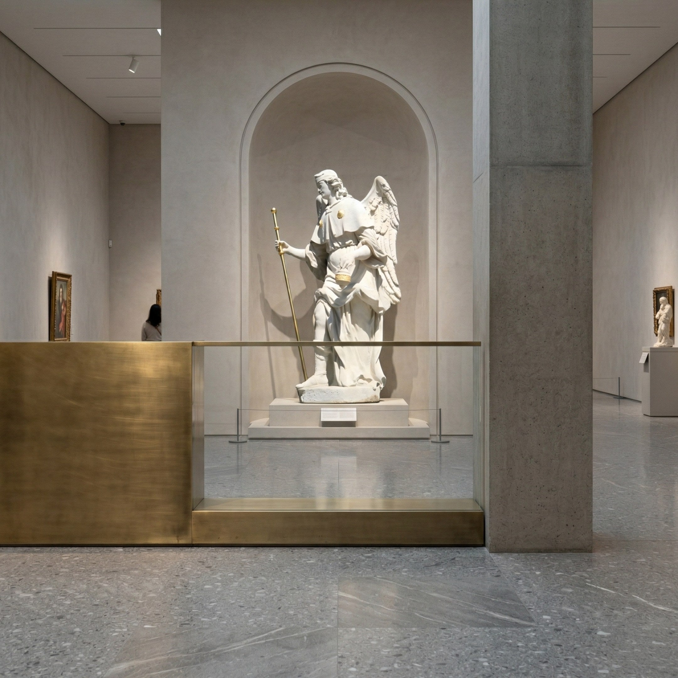 A white marble statue, the Armoured Guardian Angel Marble Outdoor Sculpture - 200cm by Giant Sculptures, stands with a staff in an arched alcove of a modern art museum, bordered by minimalistic gray walls and a gold and glass barrier. Paintings adorn nearby walls.