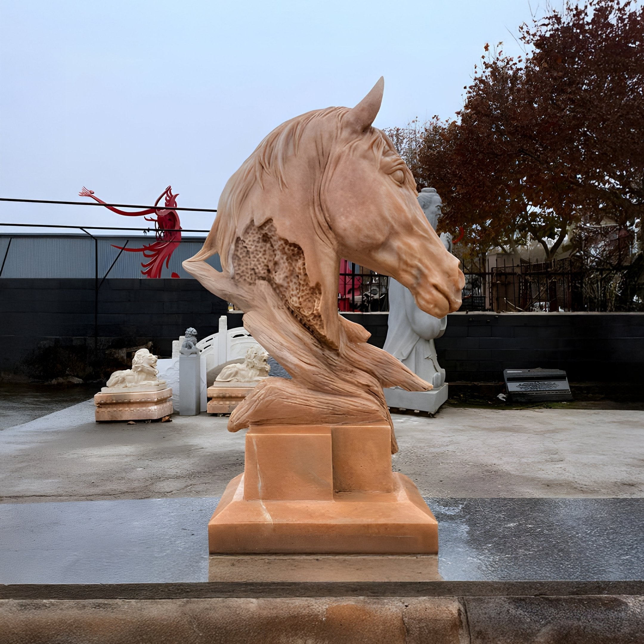 The Honeycomb Horse Head Marble Outdoor Sculpture from Giant Sculptures features dynamic, flowing details in yellow marble. With a rectangular base, it complements surrounding sculptures and trees adorned with brown leaves.