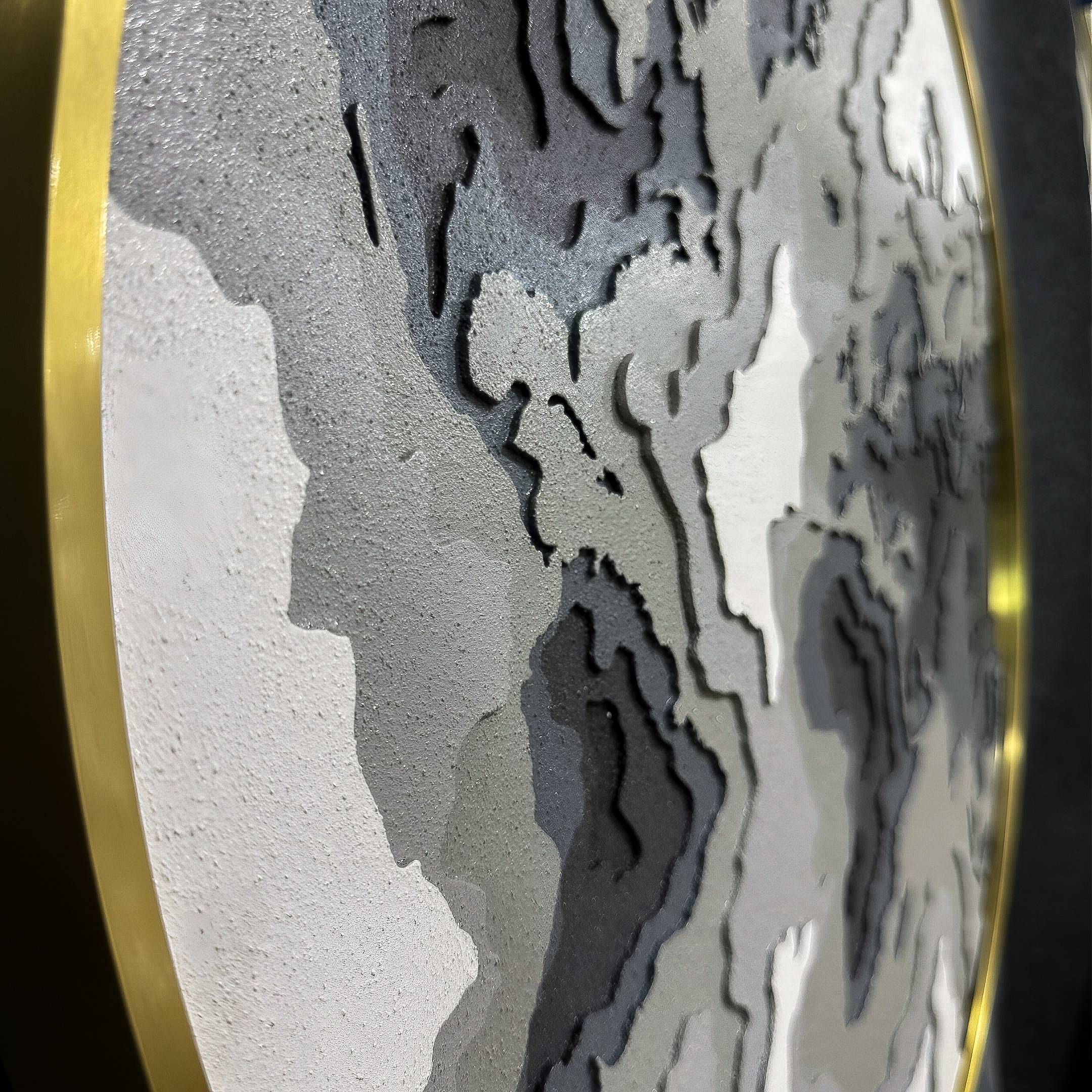 Close-up of Giant Sculptures’ Terranova Earth Green Round Wood Carving 3D Wall Art, featuring layered, textured patterns in gray, black, and white with a gold metallic rim, evoking a nature-inspired or topographic map design.