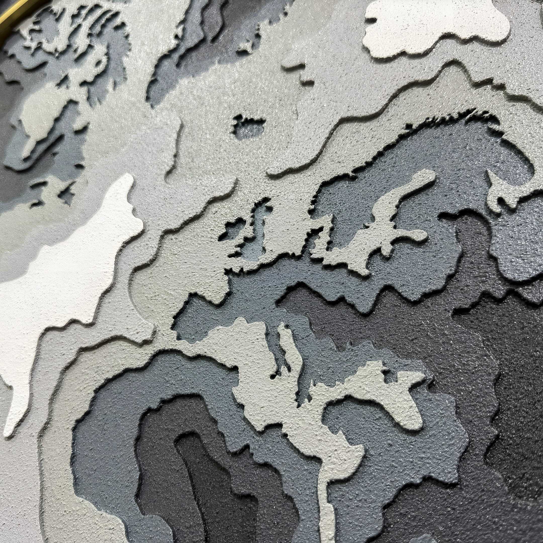 The Terranova Earth Green Round Wood Carving 3D Wall Art by Giant Sculptures features a textured, layered map design in gray, white, and black, with a stylized depiction of Europe, parts of Asia, and nearby regions.