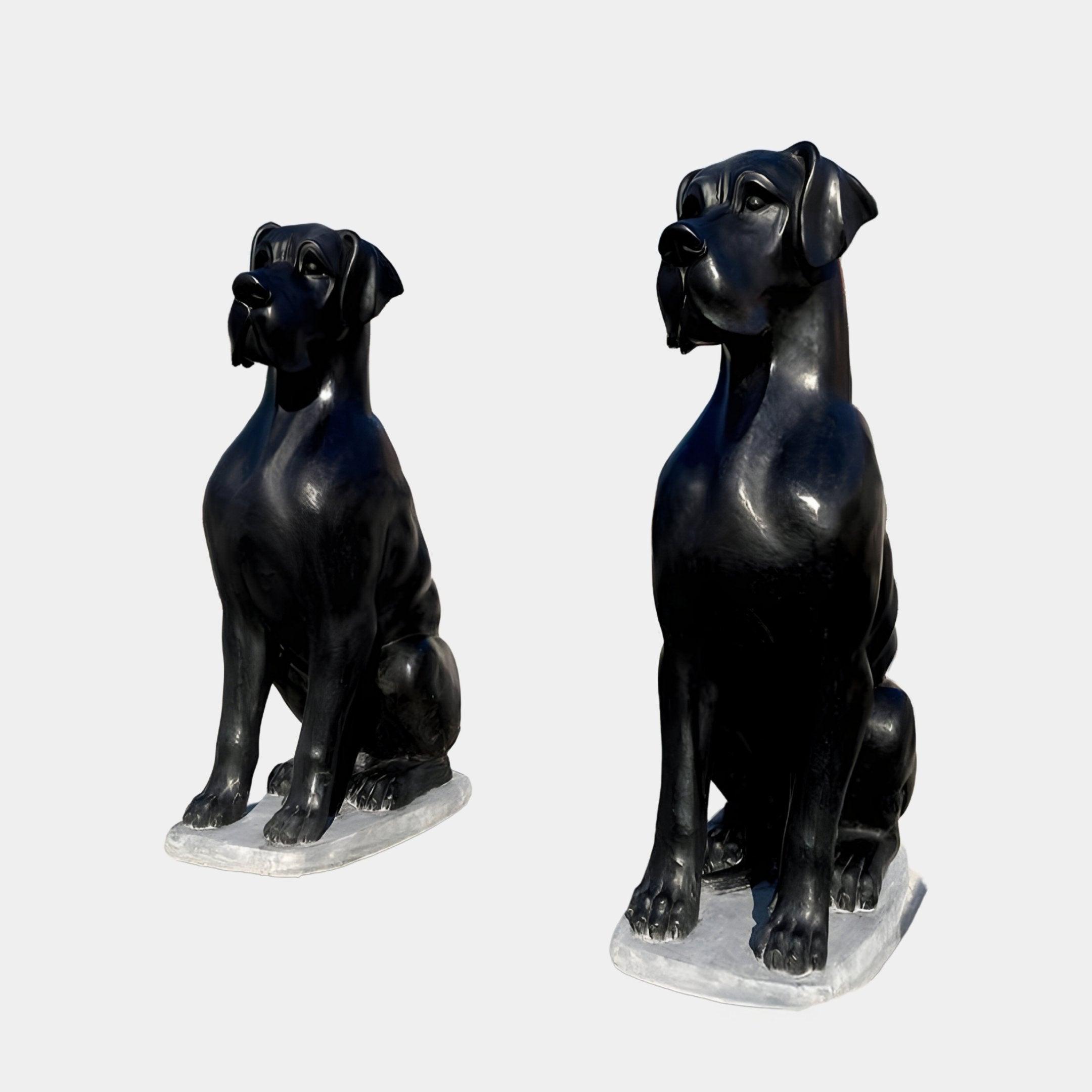 The Ebony Guardian Dog Marble Outdoor Sculptures by Giant Sculptures, standing at 150cm, showcase two identical black statues of large seated dogs on rectangular bases against a plain white background, boasting realistic features and smooth surfaces that exude regal strength.
