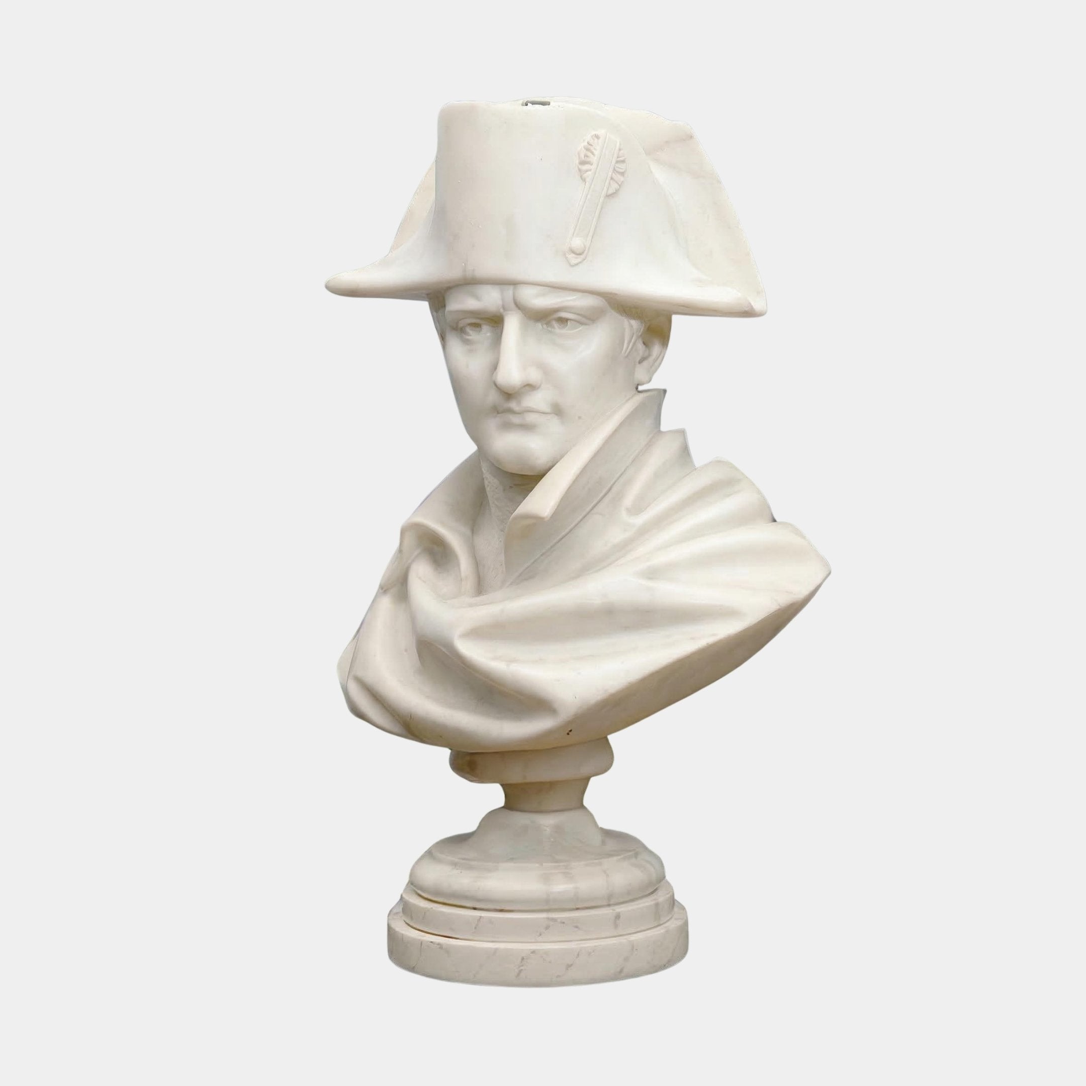 The Napoleon Marble Bust Sculpture - 65cm by Giant Sculptures features a stern-faced man in a bicorne hat and draped cloak, crafted from white marble and set on a round pedestal, perfect for elegant interiors.