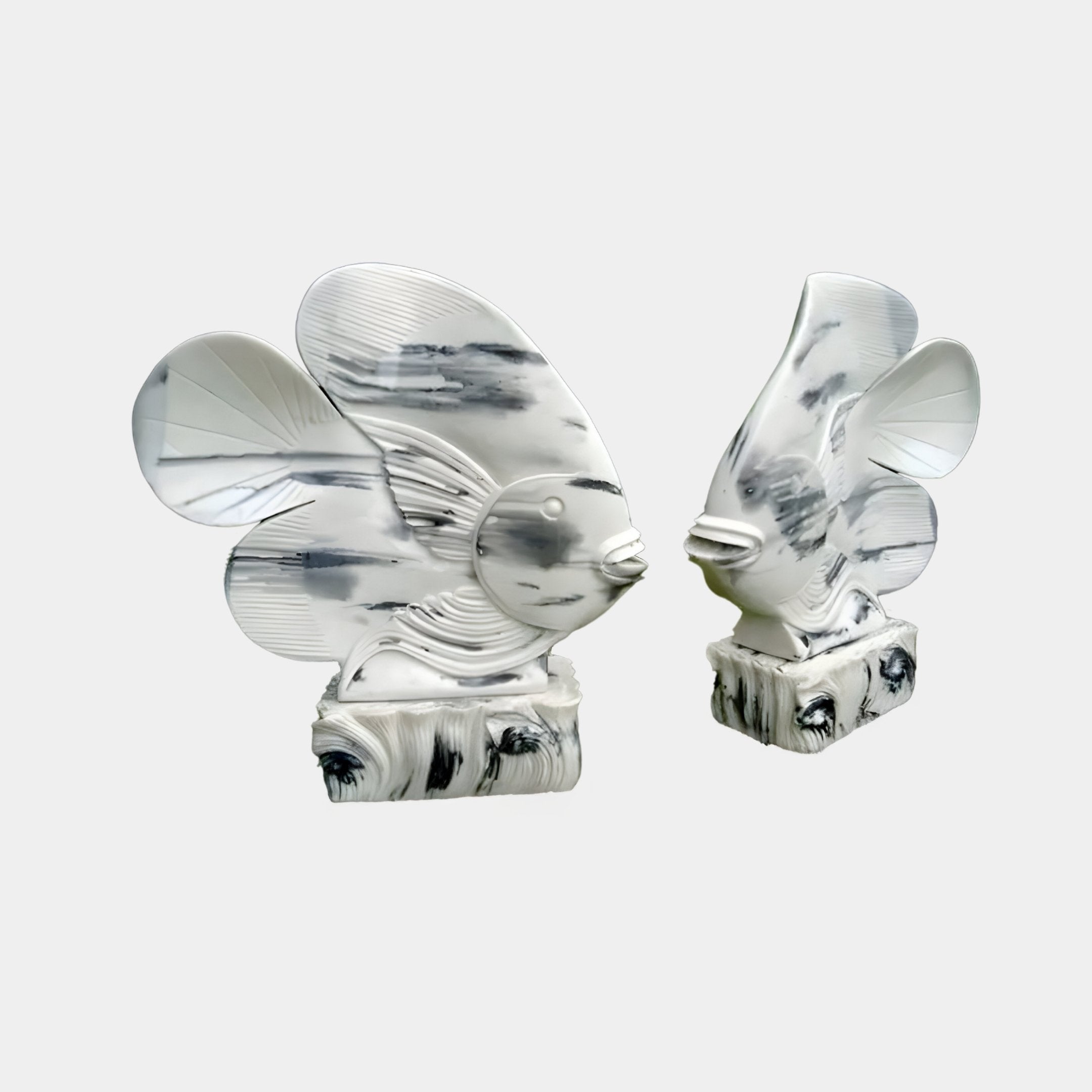 Two Swirl-Fin Angel Fish II sculptures by Giant Sculptures, elegantly designed with marble finish and intricate fin patterns, sit facing each other on matching bases. Their gray and white hues enhance their smooth texture, perfect as outdoor decor. Each piece is 40cm high.