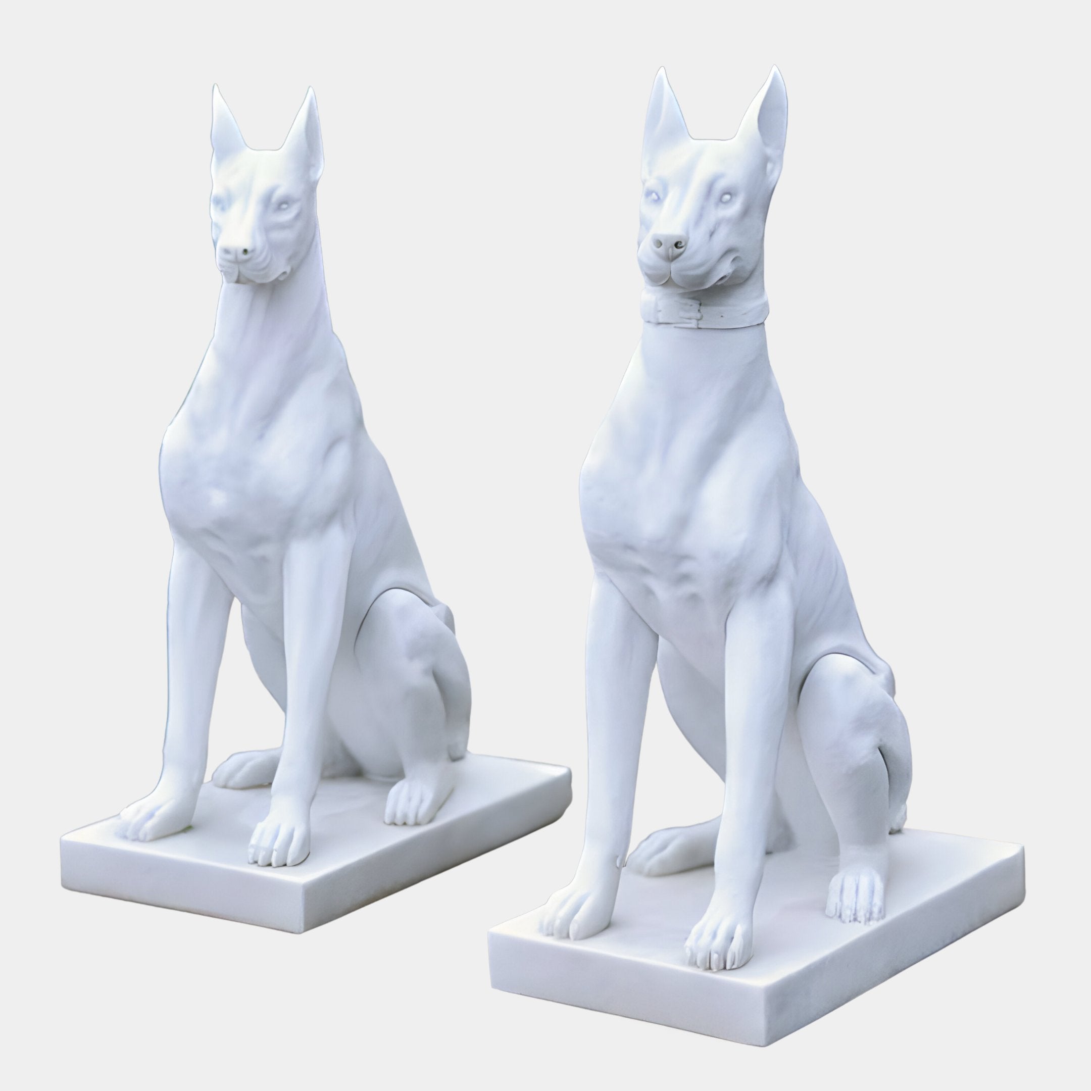 The Vigilant Guardian Dog Marble Outdoor Sculpture by Giant Sculptures features two white, life-sized dogs on rectangular bases with upright ears and alert expressions. They face forward with smooth surfaces and exquisite hand-carved detailing against a plain background, standing 120cm tall.