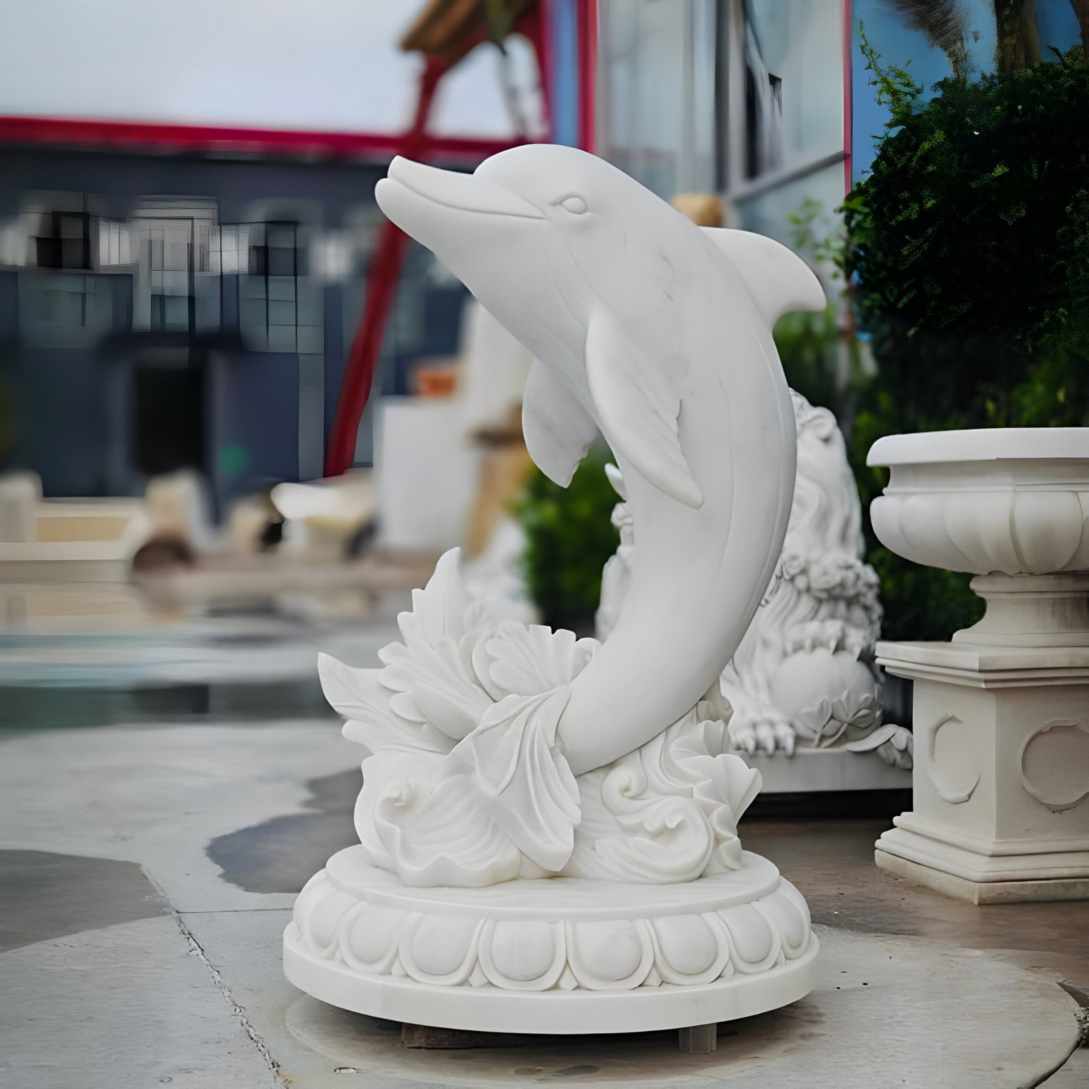 The Leaping Dolphin Marble Outdoor Sculpture by Giant Sculptures is a 150cm masterpiece depicting marine life. Its intricate design and detailed circular base make it a vibrant addition nestled among statues and lush greenery in any outdoor sculpture collection.