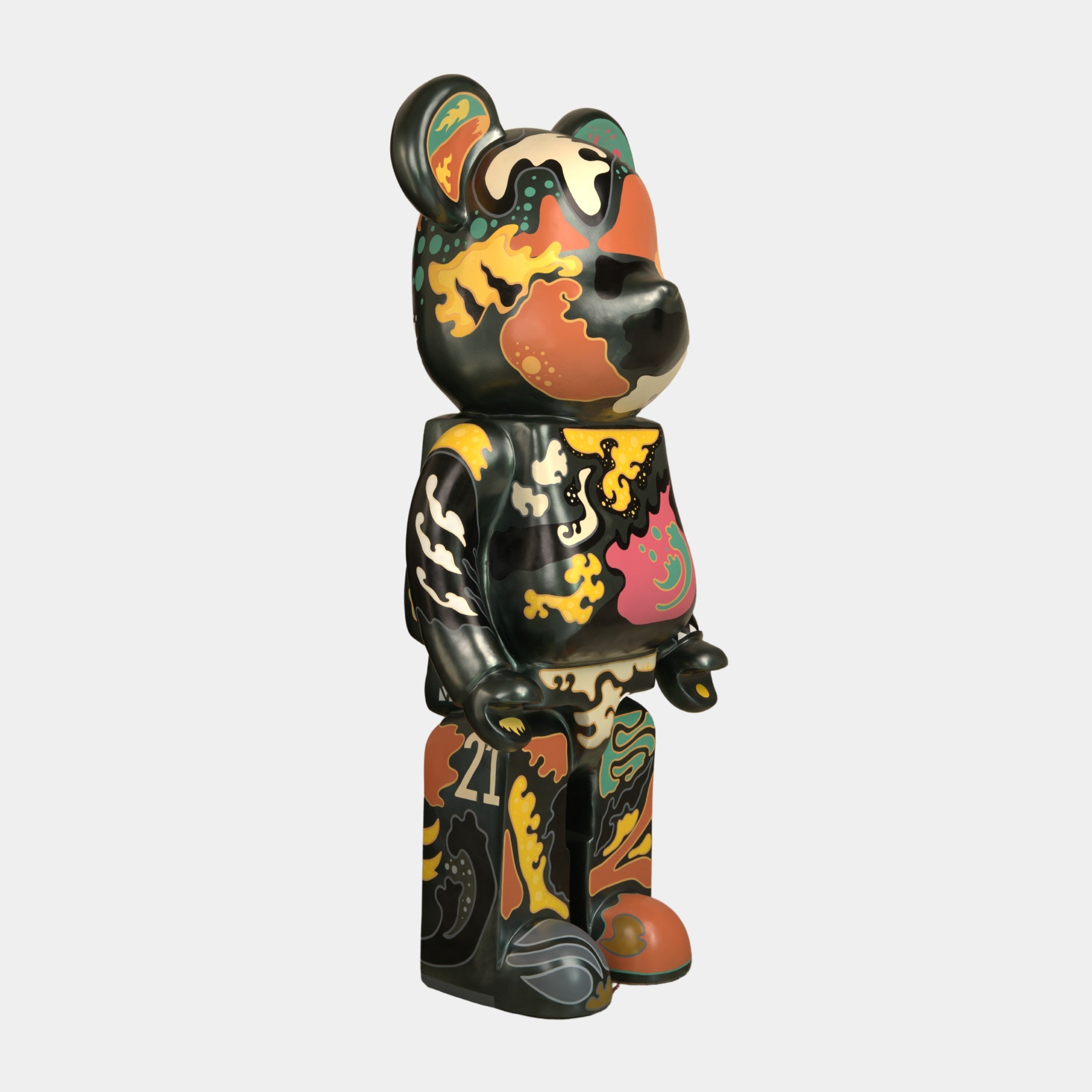 The Inside Appears Outside Bear Sculpture - 50cm by Giant Sculptures features a smooth, upright bear adorned with Jirayu Tantrakuls abstract black, orange, yellow, green, and beige patterns on a white background. Limited edition figurine.