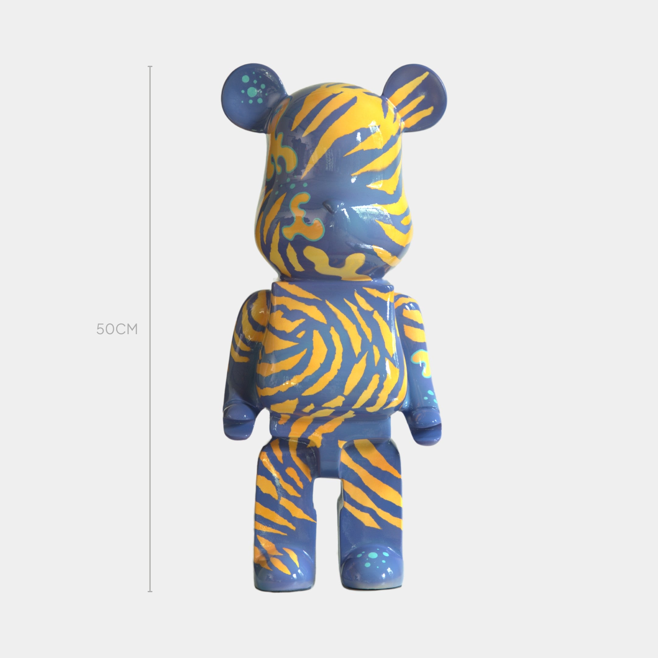 The Inside Appears Outside 2 Bear Sculpture by Giant Sculptures is a 50cm tall bear-shaped art piece with a blue body and bold yellow-orange tiger stripes, inspired by Jirayu Tantrakul and displayed on a plain white background.