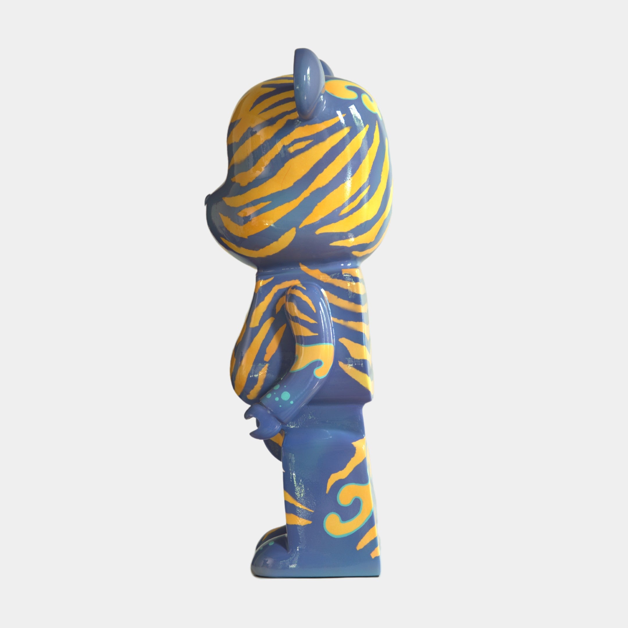 The Inside Appears Outside 2 Bear Sculpture - 135cm by Giant Sculptures, hand-painted with bold yellow tiger stripes and teal accents, is shown in a side view standing upright against a plain white background.