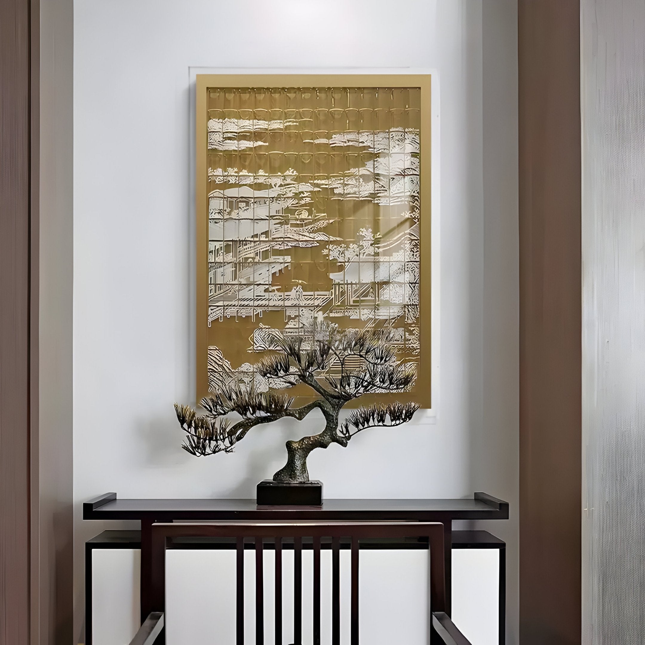 A small bonsai tree sits on a dark wooden table against a white wall, with Dynasty Dark Gold Landscape Acrylic 3D Wall Art by Giant Sculptures, featuring intricate designs, hanging above.