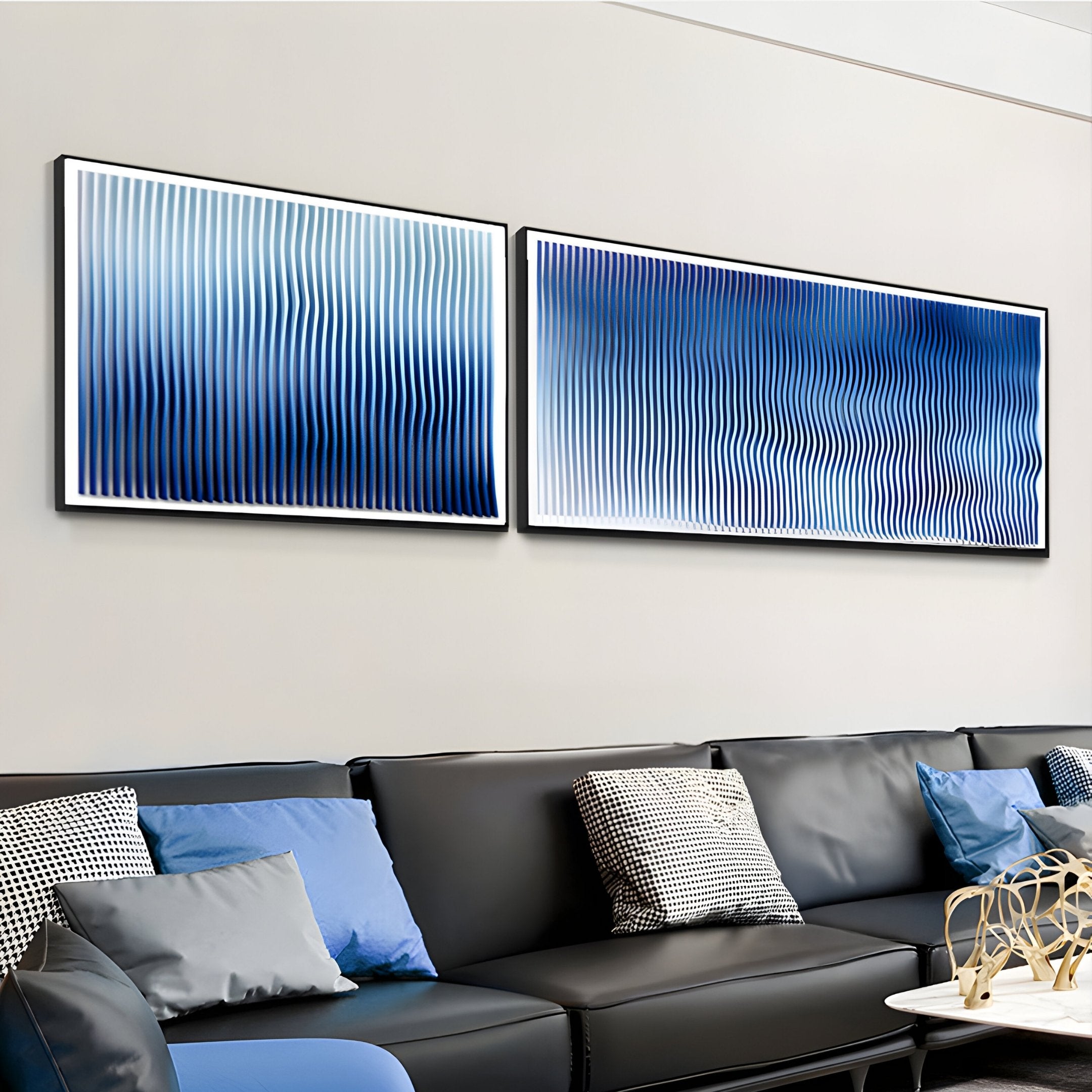 A modern living room features a black leather sofa, blue and patterned cushions, and Giant Sculptures’ Current I Navy Sky & Icy White Acrylic 3D Wall Art with wavy lines that add depth to the light wall.