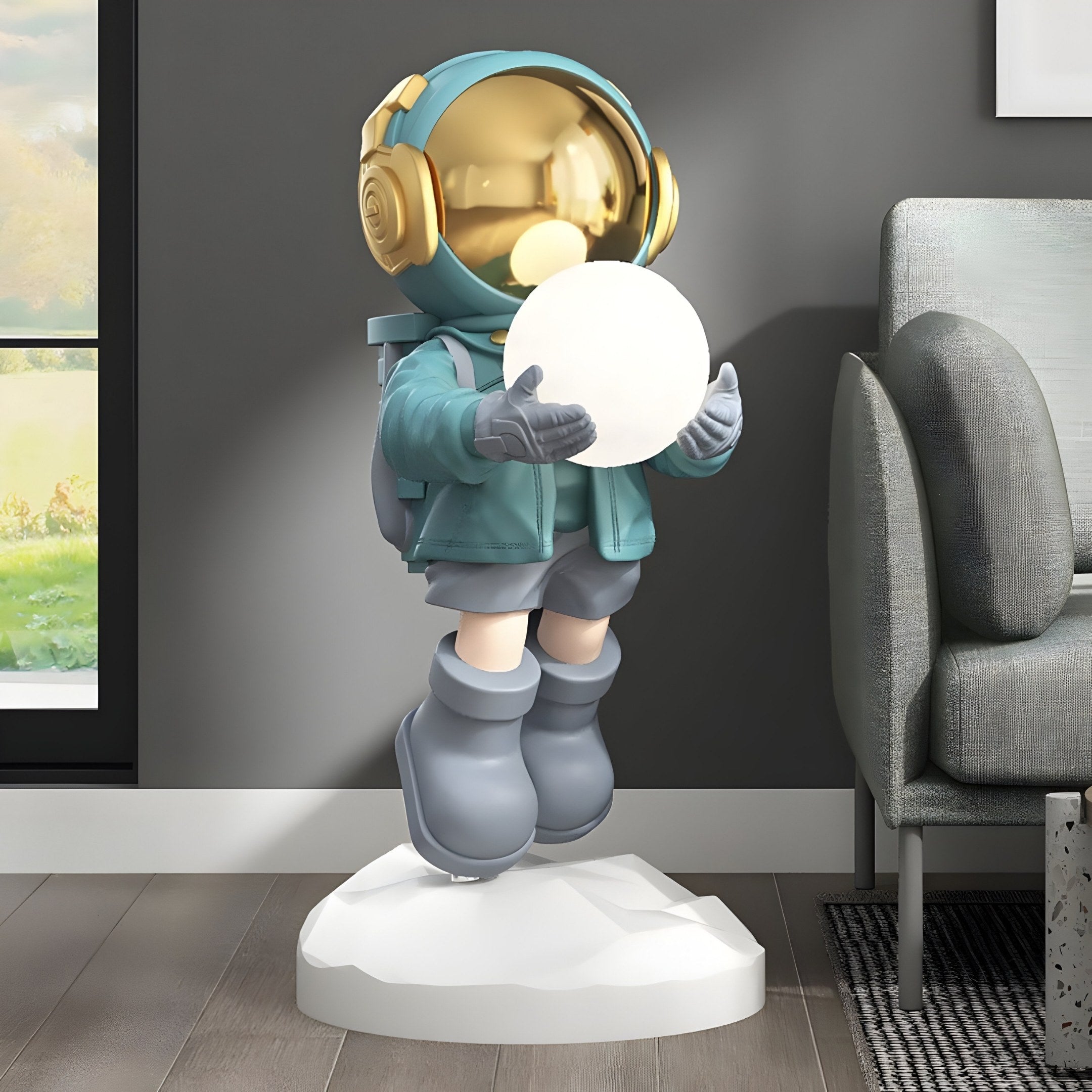 The Galactic Blue Astronaut Glow Hover Sculpture from Giant Sculptures, standing 120cm tall with a golden helmet and blue outfit, holds a glowing orb on a white base. This battery-powered lamp is next to a gray couch on a wooden floor, with sunlight streaming through the window.
