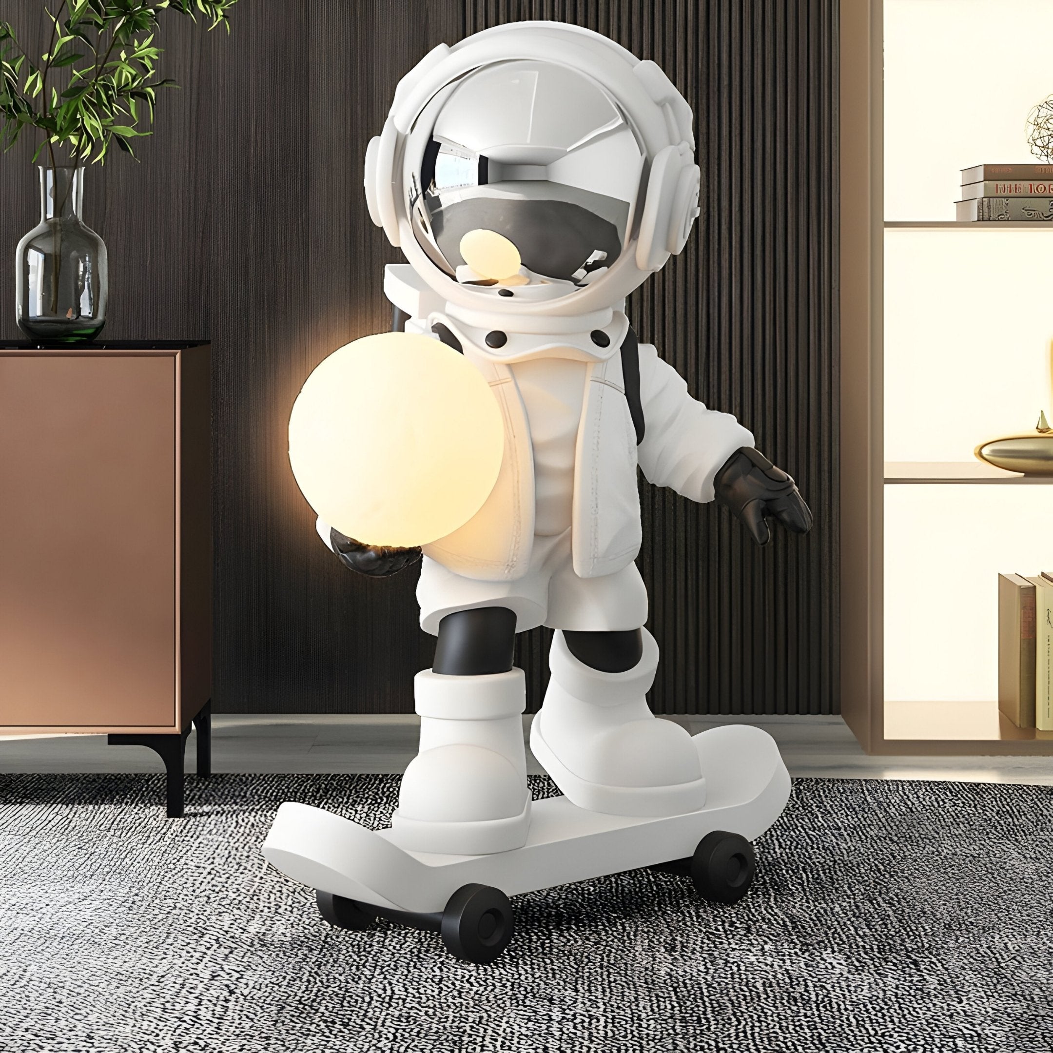 Nova White Skater Astronaut Glow Sculpture by Giant Sculptures, 80cm resin astronaut on a skateboard holding a glowing orb, styled in a modern living room with dark panelled wall and neutral furniture.