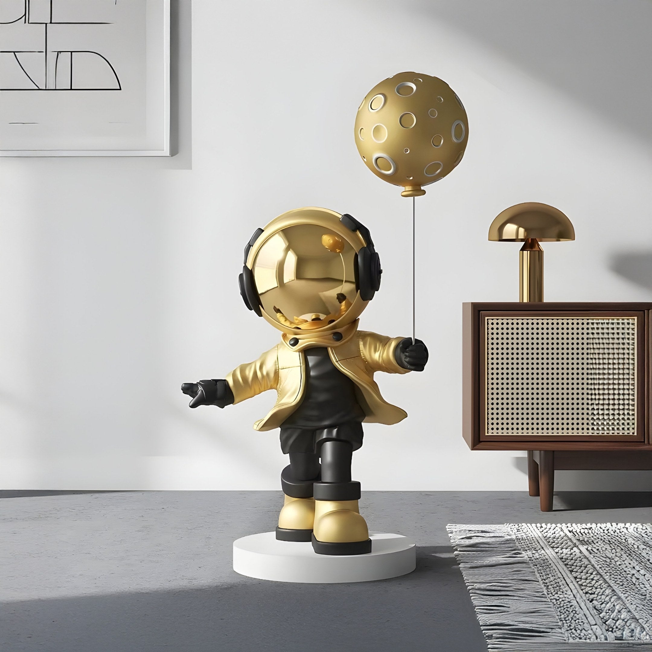 The Celestial Gold Astronaut Moon Balloon Sculpture (96cm) by Giant Sculptures features a child in a gold helmet and jacket with black pants, holding a moon balloon on a circular base, adding cosmic elegance to minimalist spaces with geometric decor.