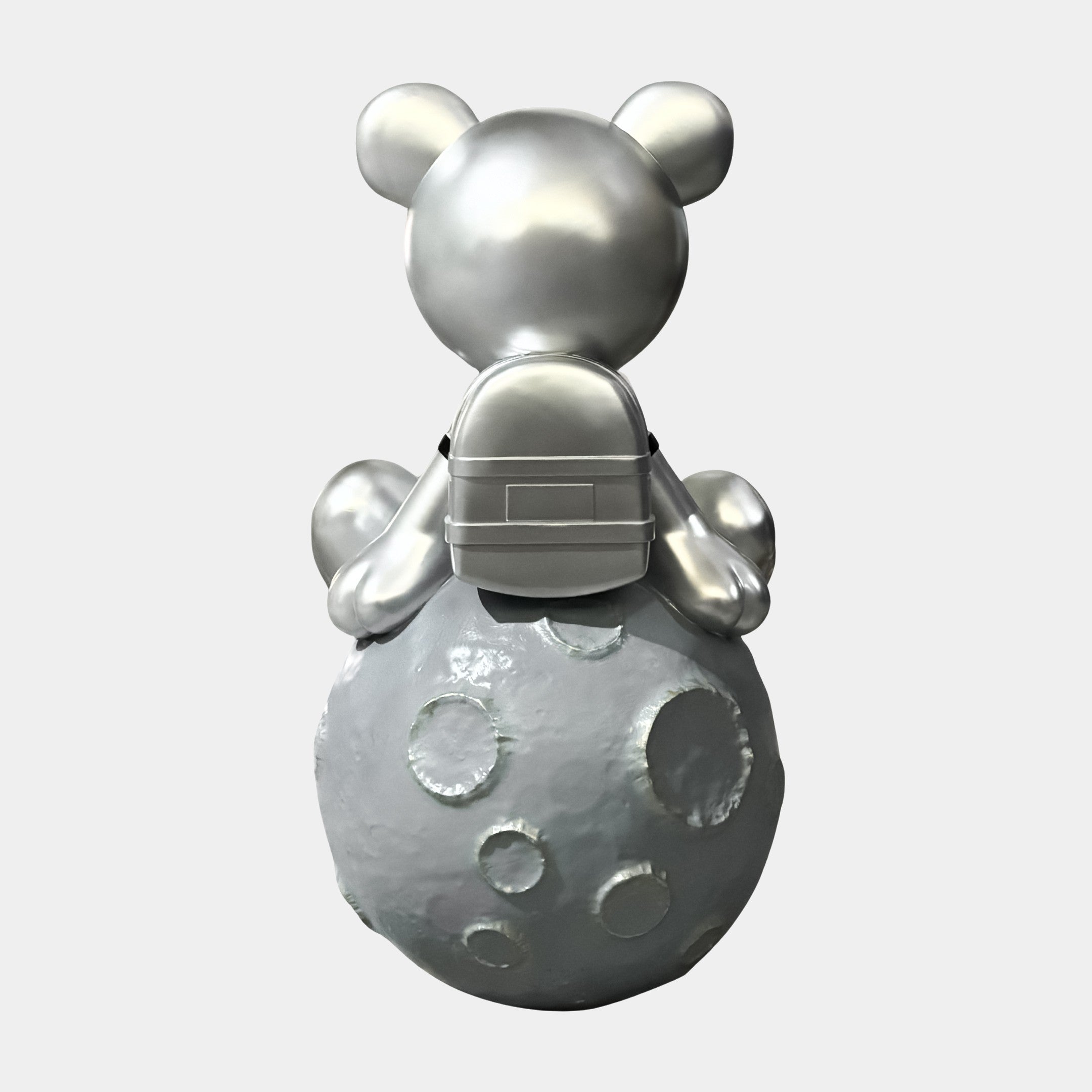 The Giant Sculptures Cosmic Chrome Astronaut Bear Moon Sculpture (80cm) features a reflective-visored bear with a backpack, sitting on a textured gray moon and viewed from behind against a plain white background.