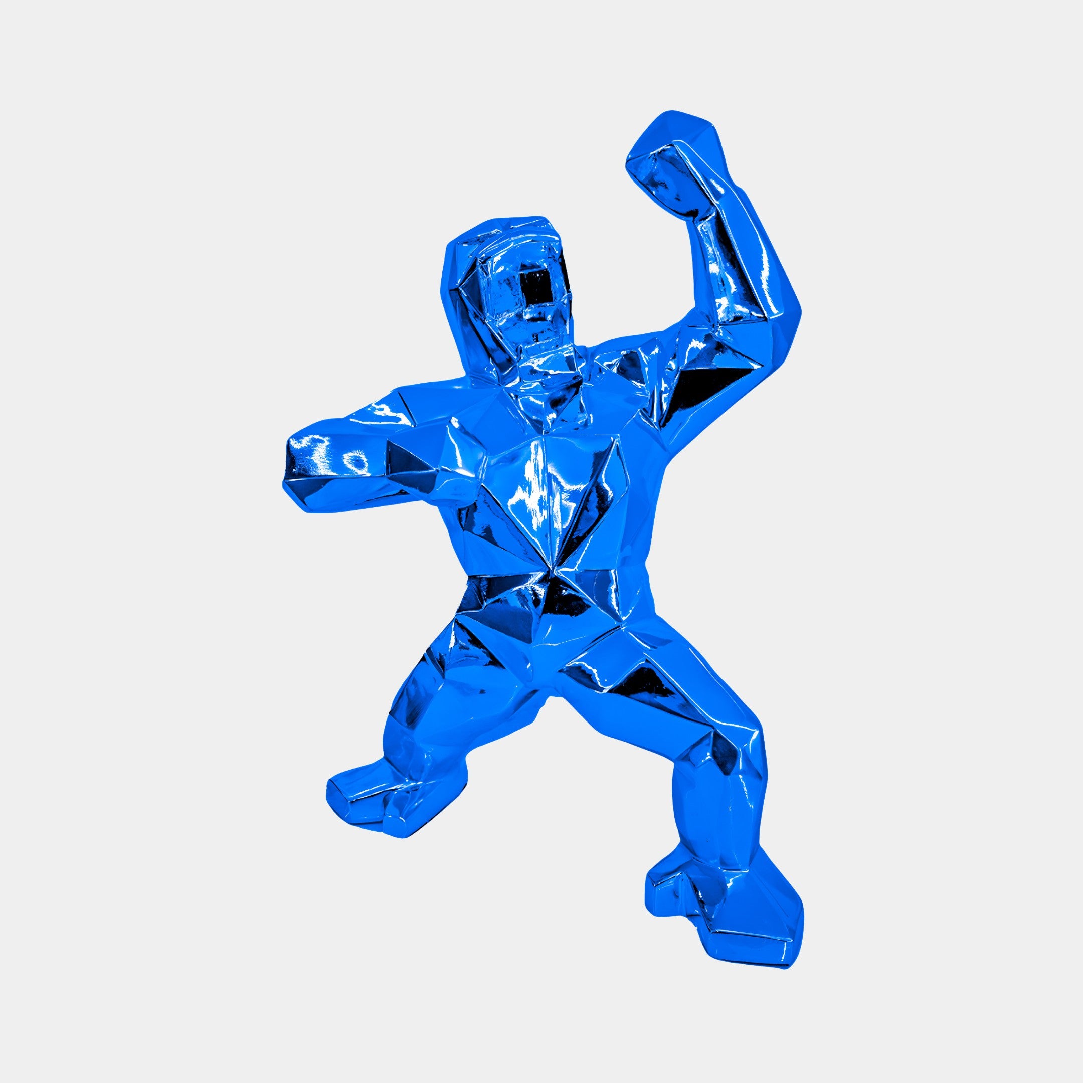 The Sapphire Blue Gorilla Sculpture (50cm) by Giant Sculptures showcases contemporary design with its shiny, faceted form. Standing on wide-set legs, it features a human-like figure with one arm raised and mouth open, embodying strength and poise in vibrant blue.
