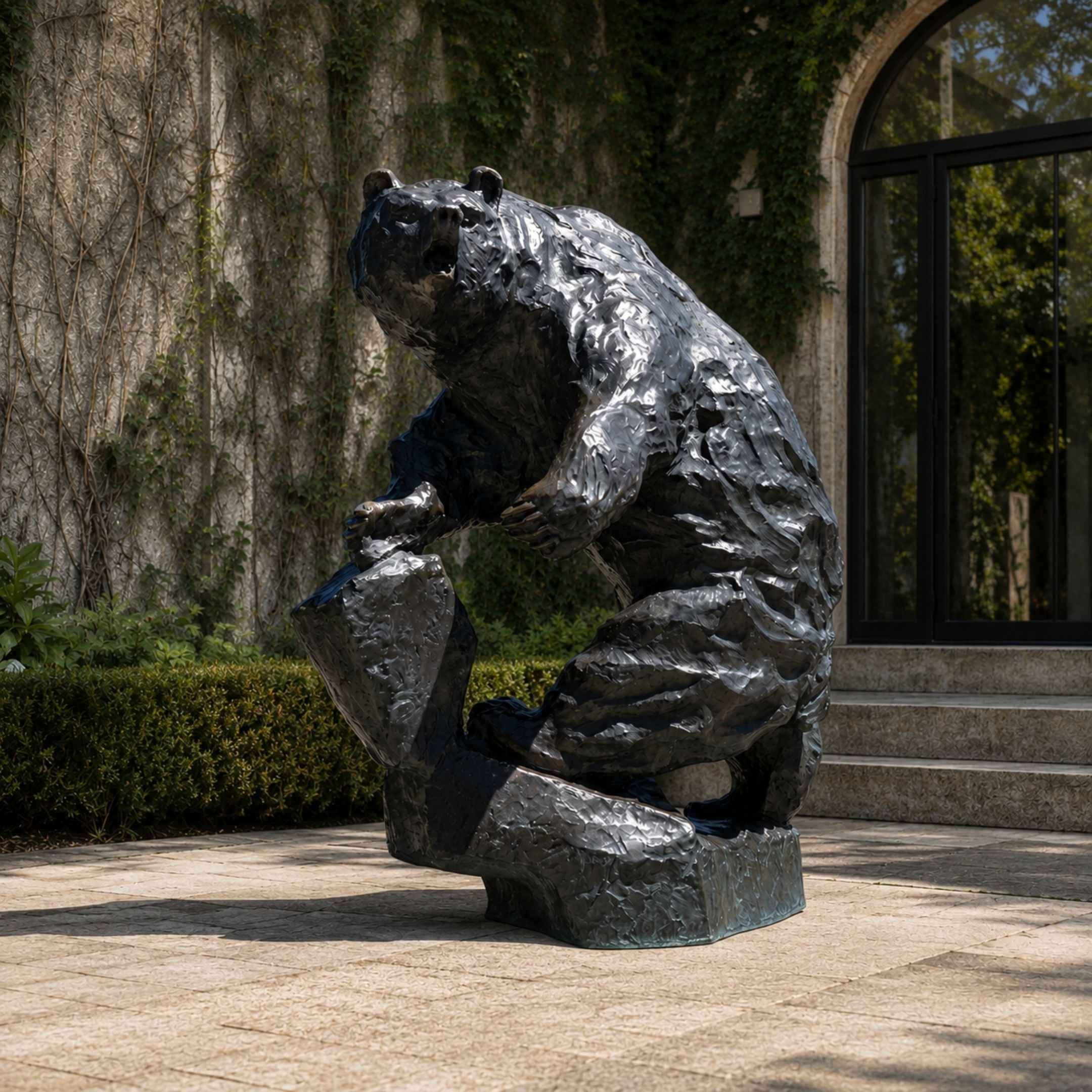 Monumental Rearing Grizzly Bear Bronze Sculpture by Giant Sculptures, shown seated on a rock with polished dark patina, displayed on a paved courtyard.
