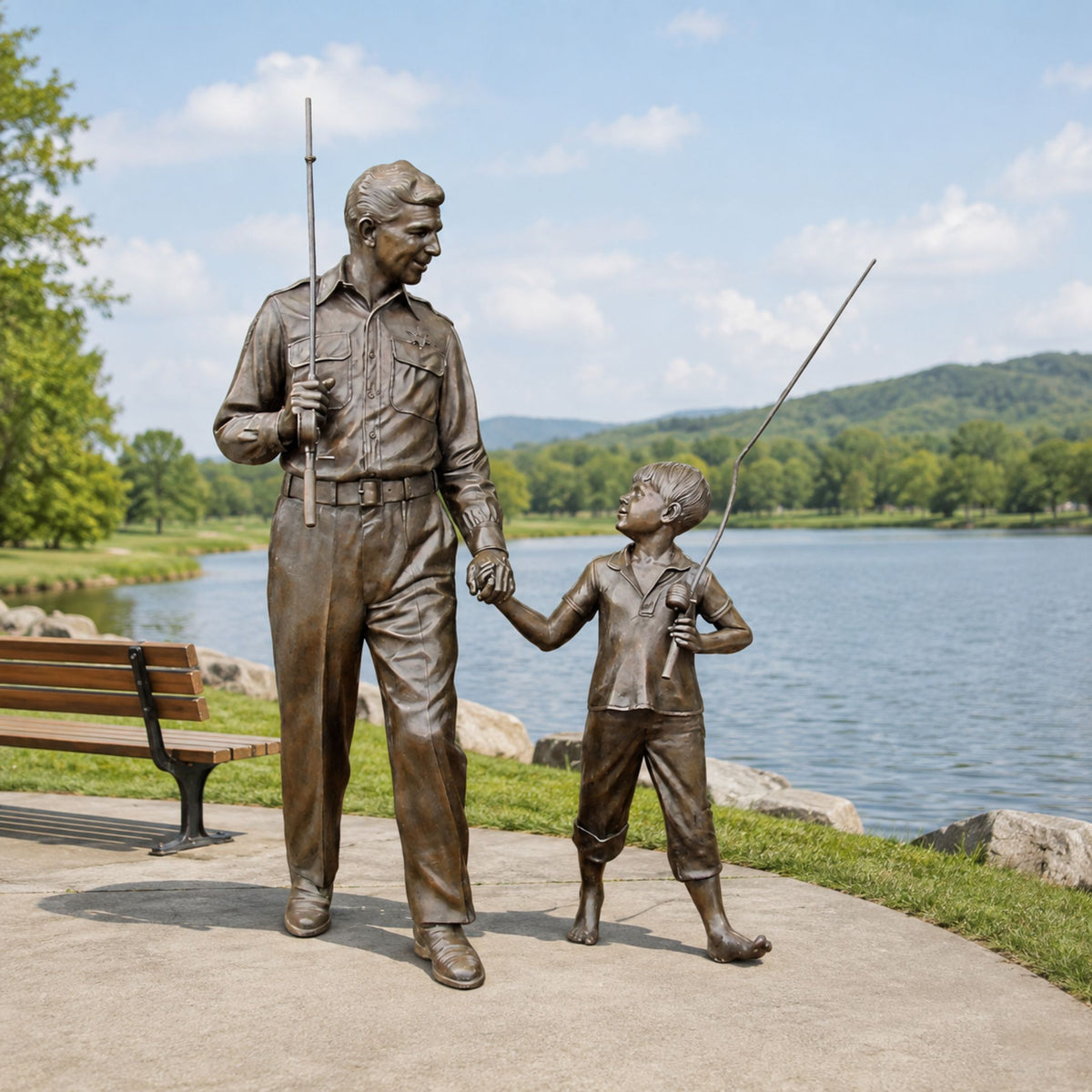 Life-Size Traditional Man and Boy Fishing Bronze Sculpture, 230cm, by Giant Sculptures, showing a man and boy holding fishing rods beside a lakeside path with a bench and water view.