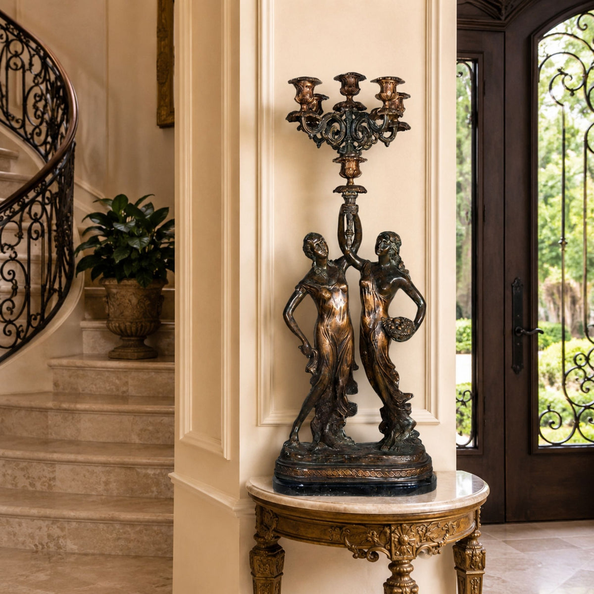 Classical Two Female Figures Candelabra Bronze Sculpture, 90cm, shown on a marble-top console table beside a curved staircase in an entryway.