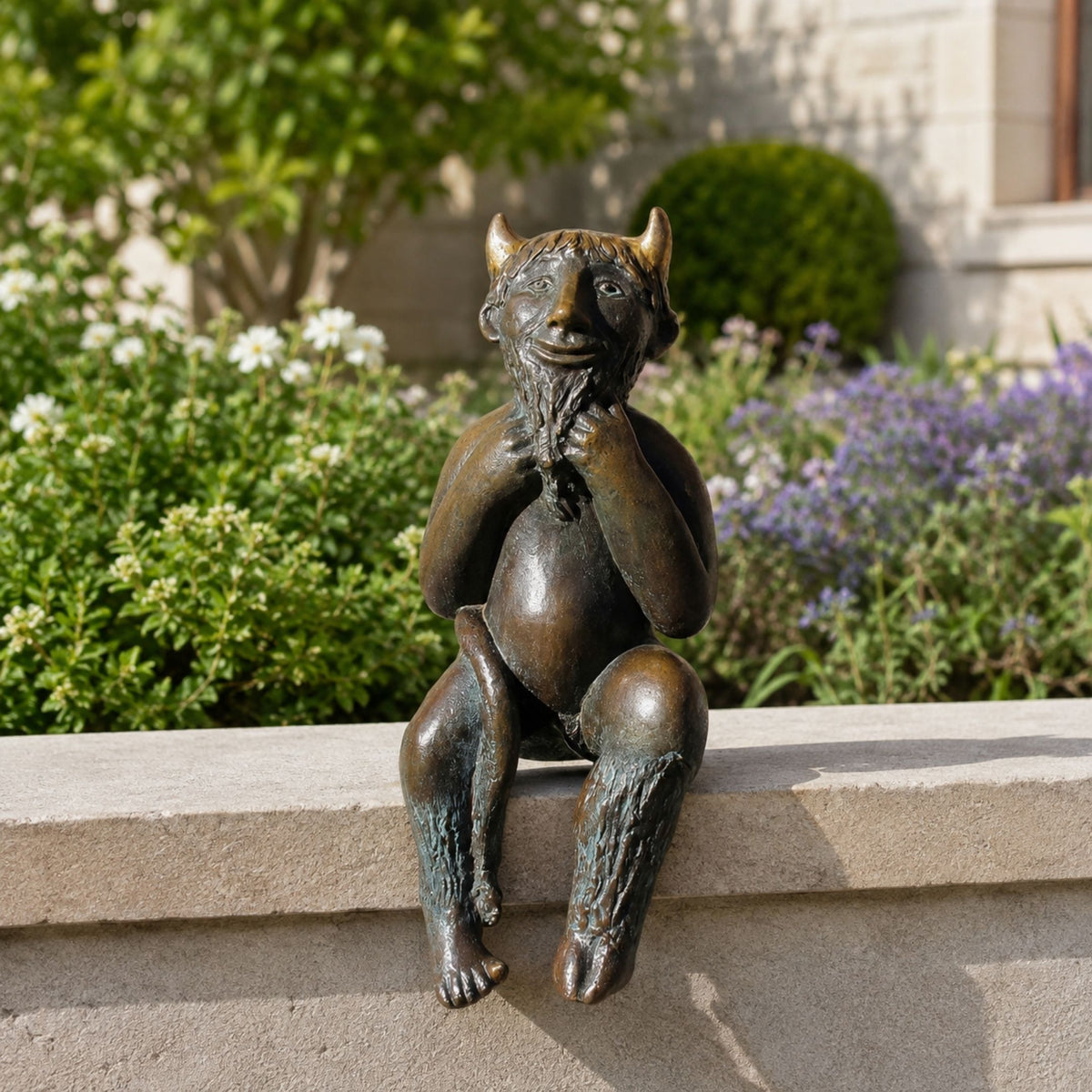 Traditional Seated Faun Bronze Sculpture, 80cm, cast bronze faun with horns and braided beard, hands to chin, seated on a stone ledge amid garden greenery.