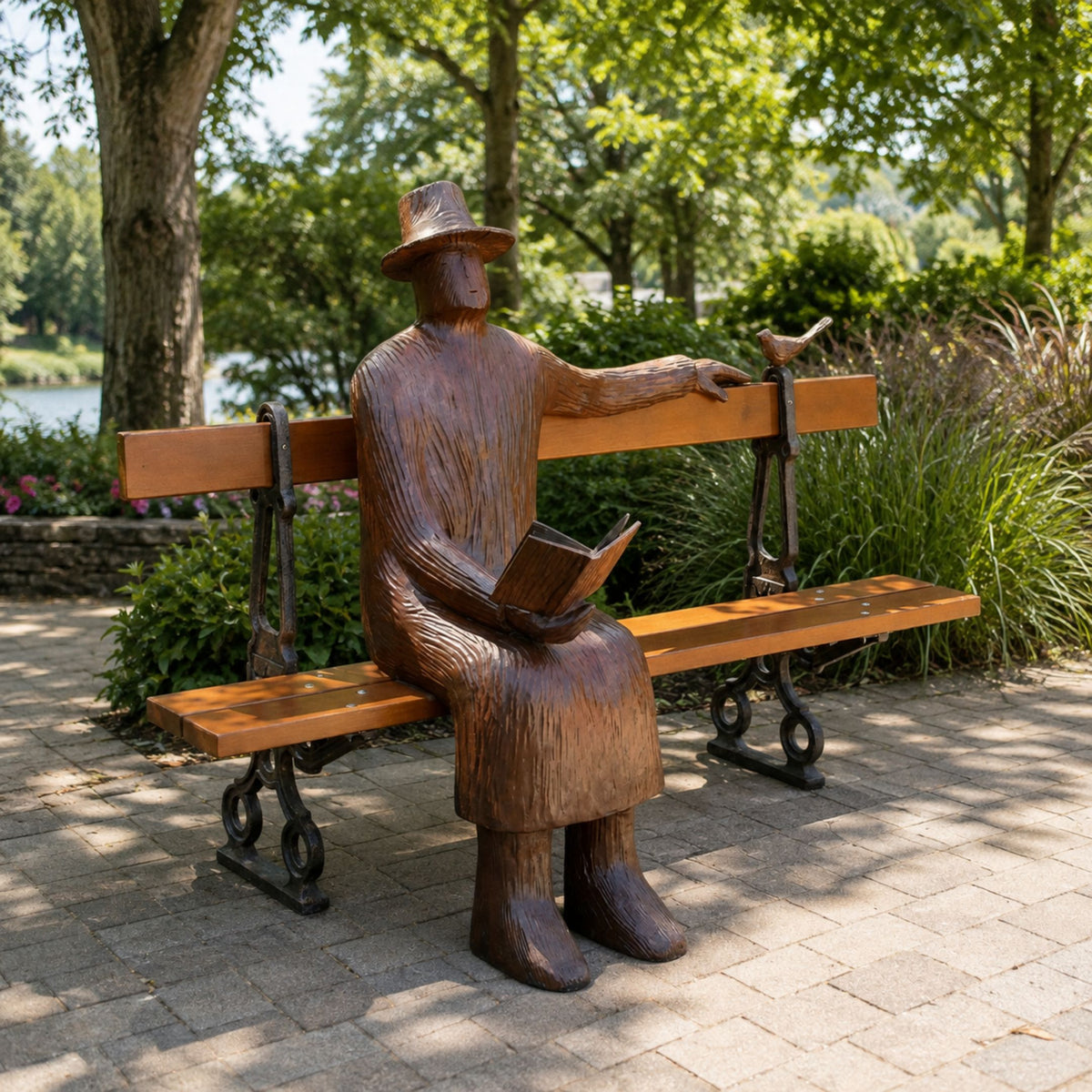 Life-Size Modern Seated Reader Bronze Sculpture, 170cm, hat-wearing figure on a park bench with a bird on its hand and a book in its lap, outdoor garden setting.