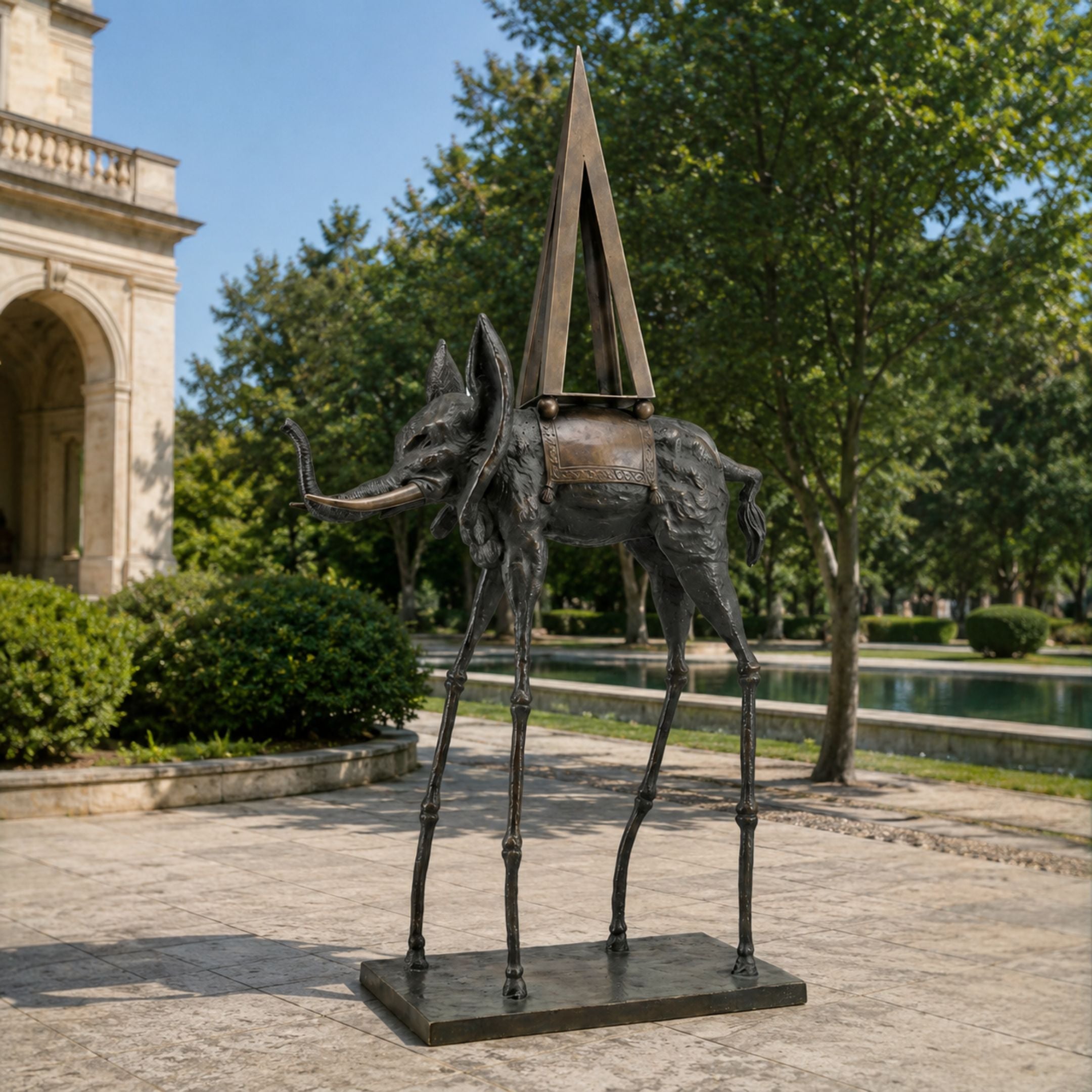 Monumental Contemporary Surrealist Elephant Bronze Sculpture, 350cm, with spindly stilt-like legs, flared ears, and a tall triangular spire on its back, displayed outdoors near trees and a courtyard.