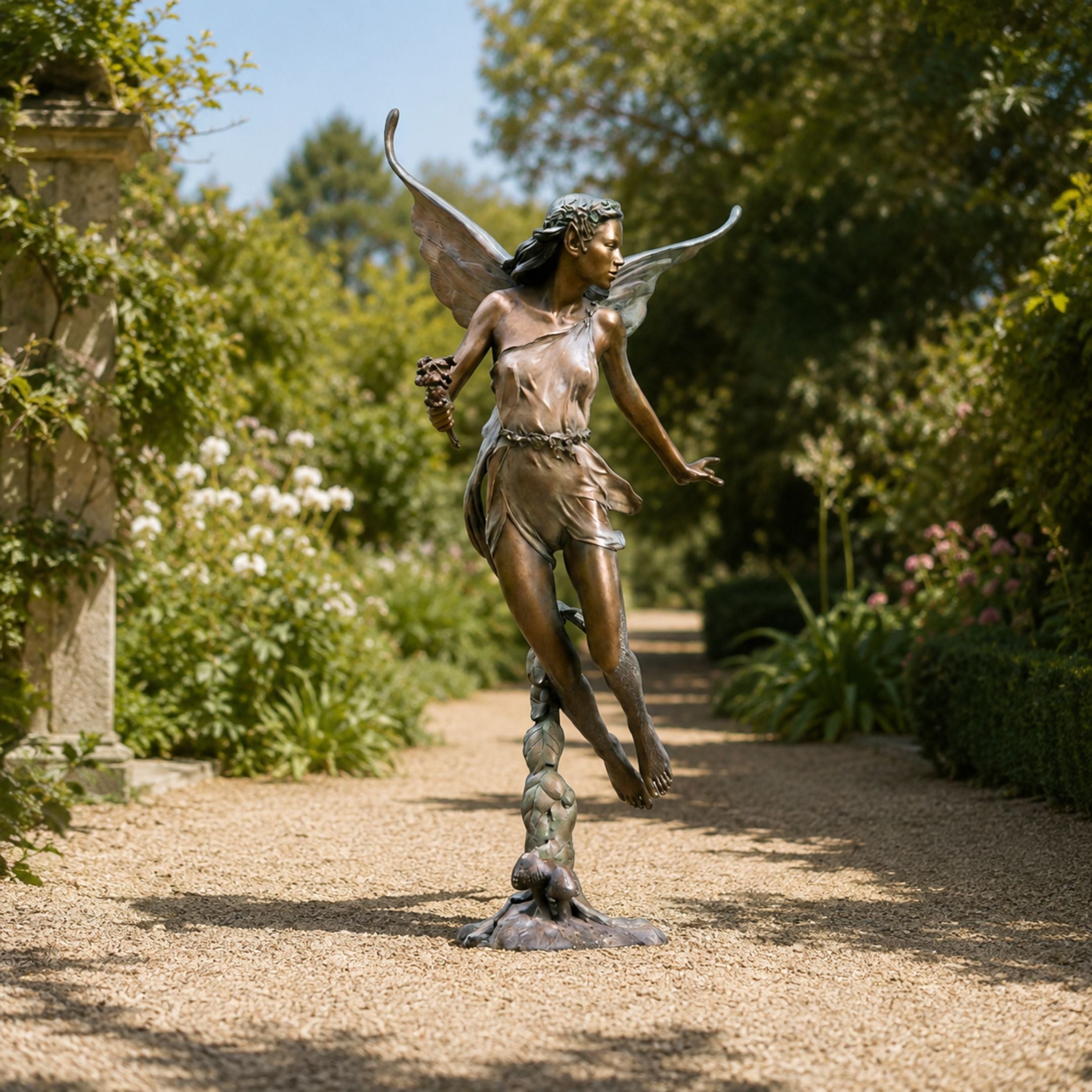 Large Classical Winged Fairy Figure Bronze Sculpture, 150cm, on tiptoe with wings spread and floral crown, displayed on a gravel garden path.