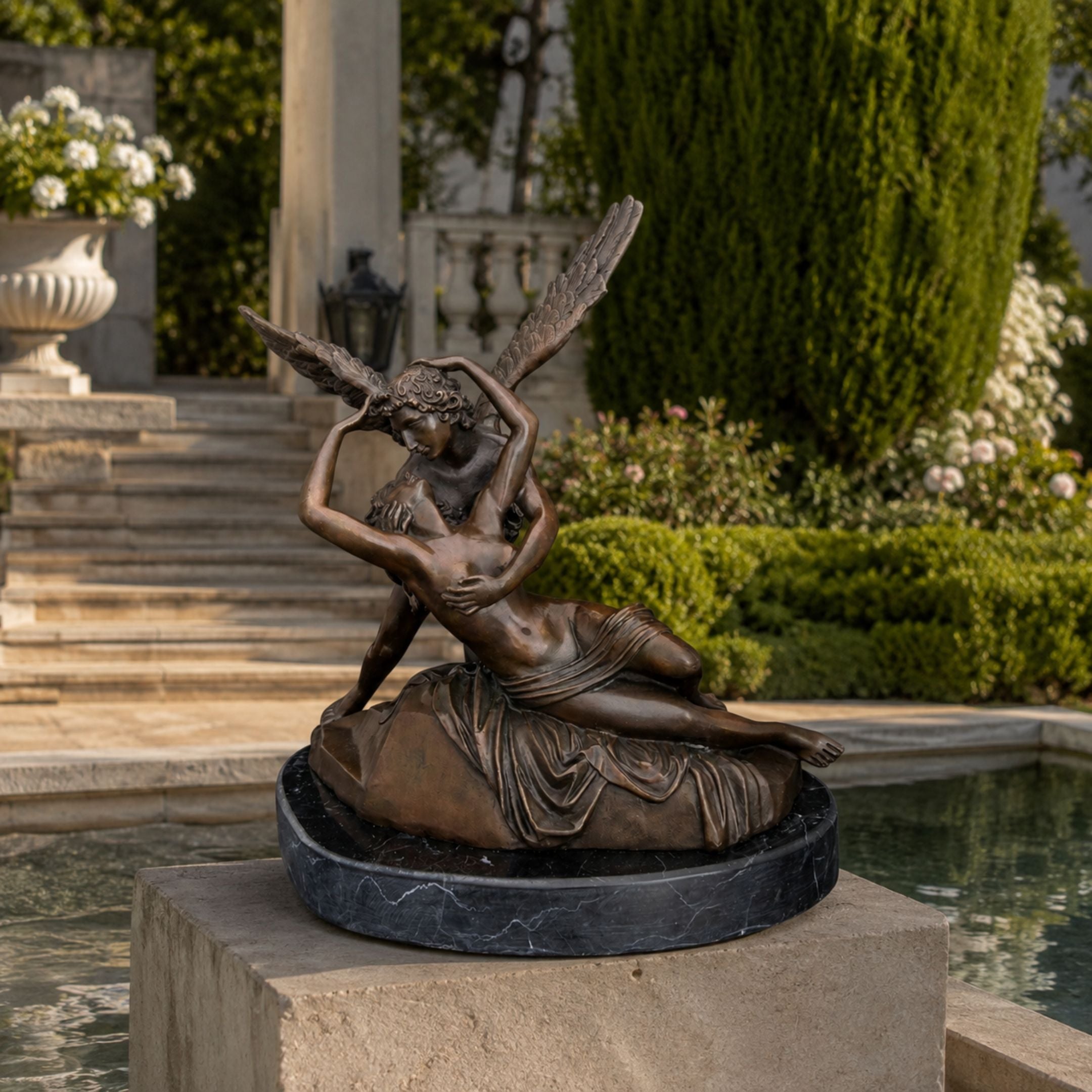 Large Classical Cupid and Psyche Bronze Sculpture, 150cm, winged Cupid embracing reclining Psyche on a round black marble base, displayed by a garden fountain.