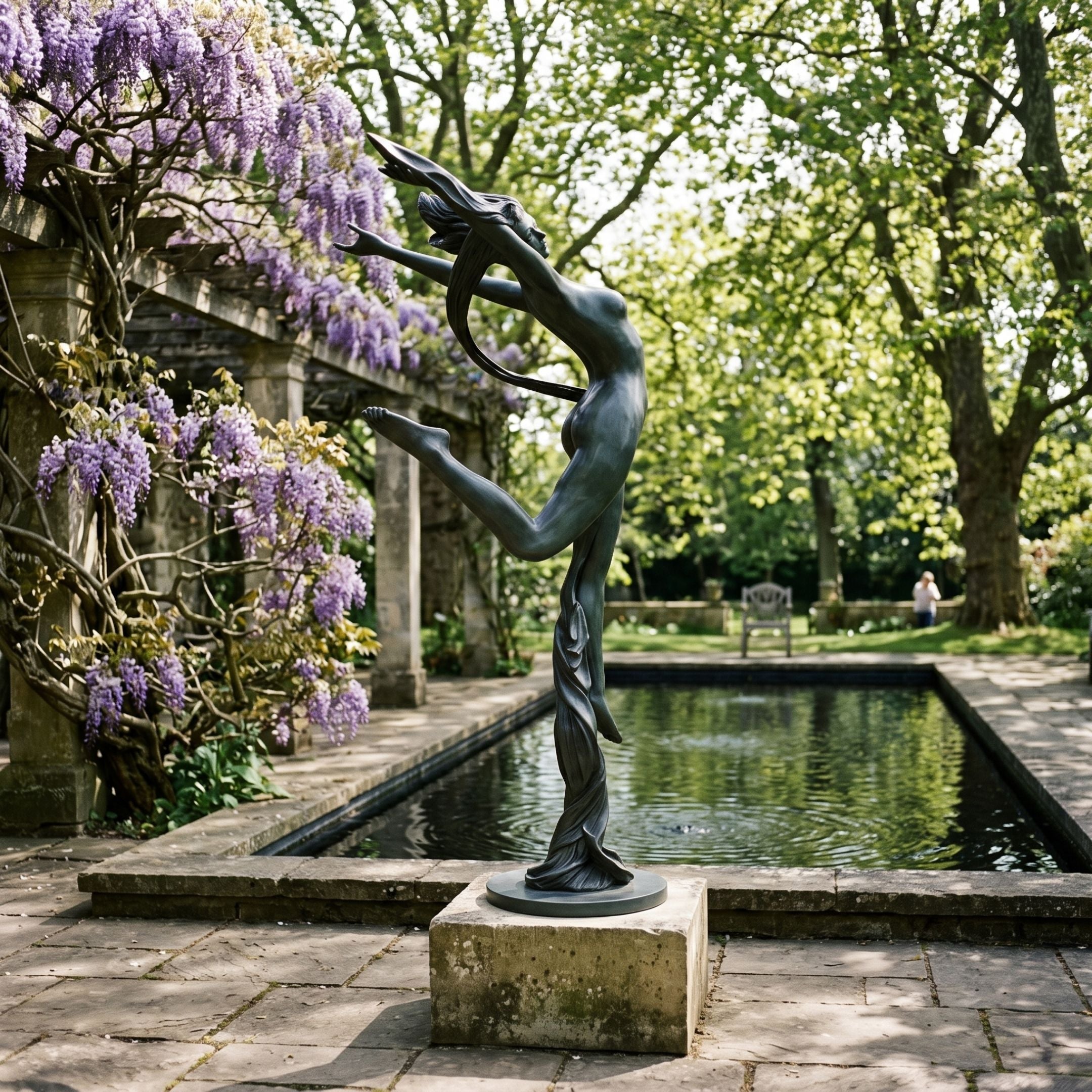 Life-Size Nude Ribbon Dancer Bronze Sculpture, 240cm, in deep verdigris patina on a stone plinth beside a garden pool with wisteria and trees.