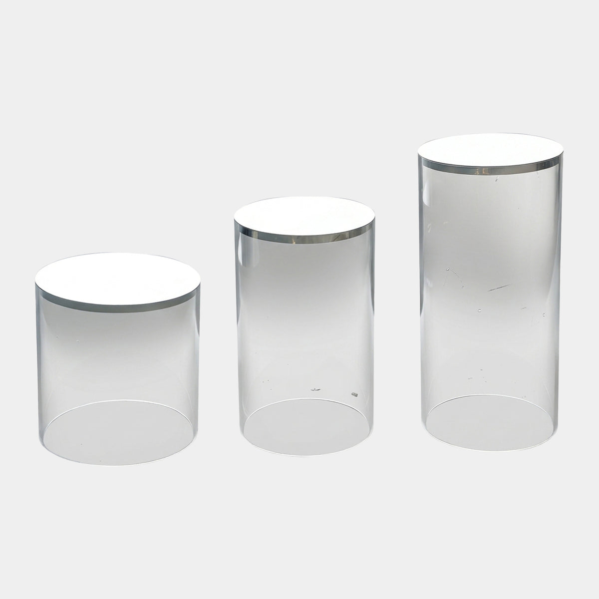 Clear & White Cylinder Acrylic Display Plinth Set of Three - 70cm, three clear acrylic cylinders with white tops and polished metal rims at varying heights on a plain white background.