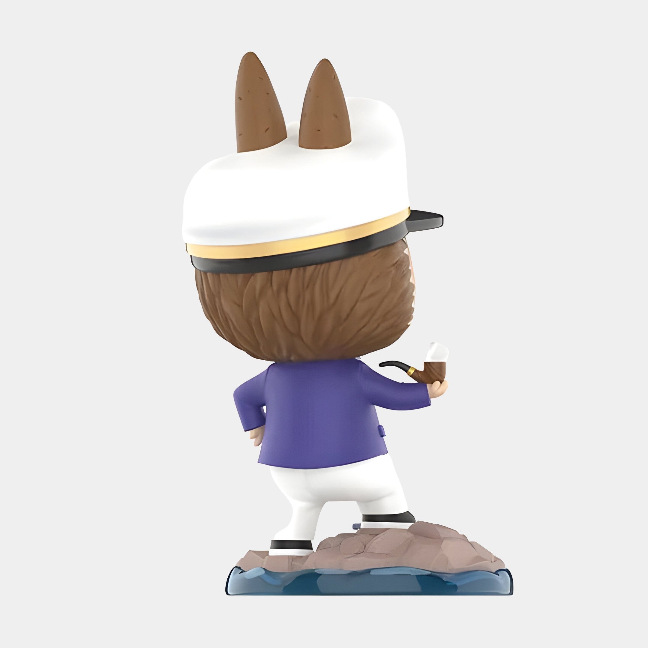 The Giant Sculptures Monster Captain Labubu Sculpture - 160cm depicts a horned animal in a captain’s hat and blue jacket, standing confidently on a rocky base with pipe in hand, facing away from the viewer.