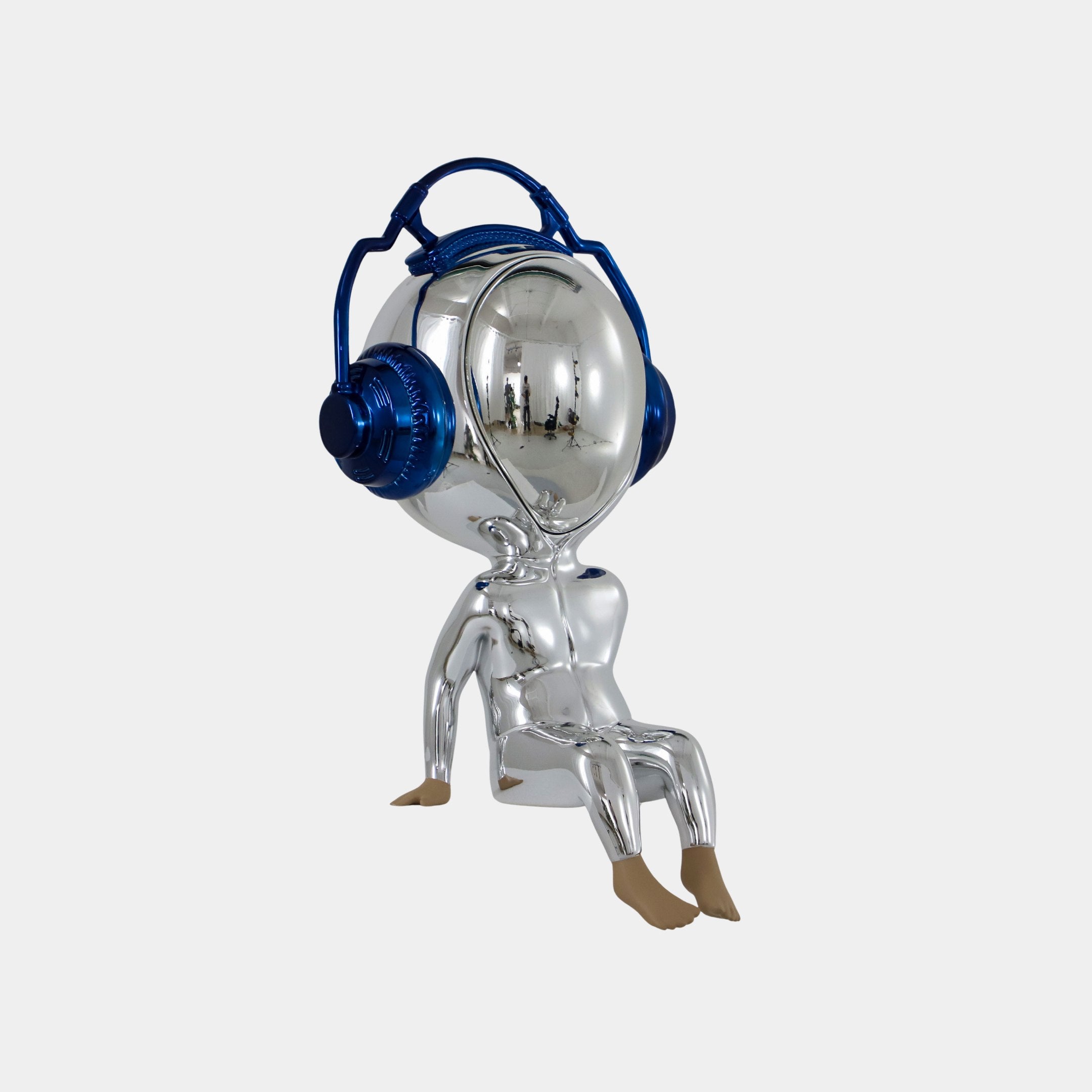 The Midnight Chrome Alien Beats Figure (55cm) by Giant Sculptures features a shiny silver humanoid with a round head, mirrored visor, oversized metallic blue headphones, beige feet, and sits against a plain white background.