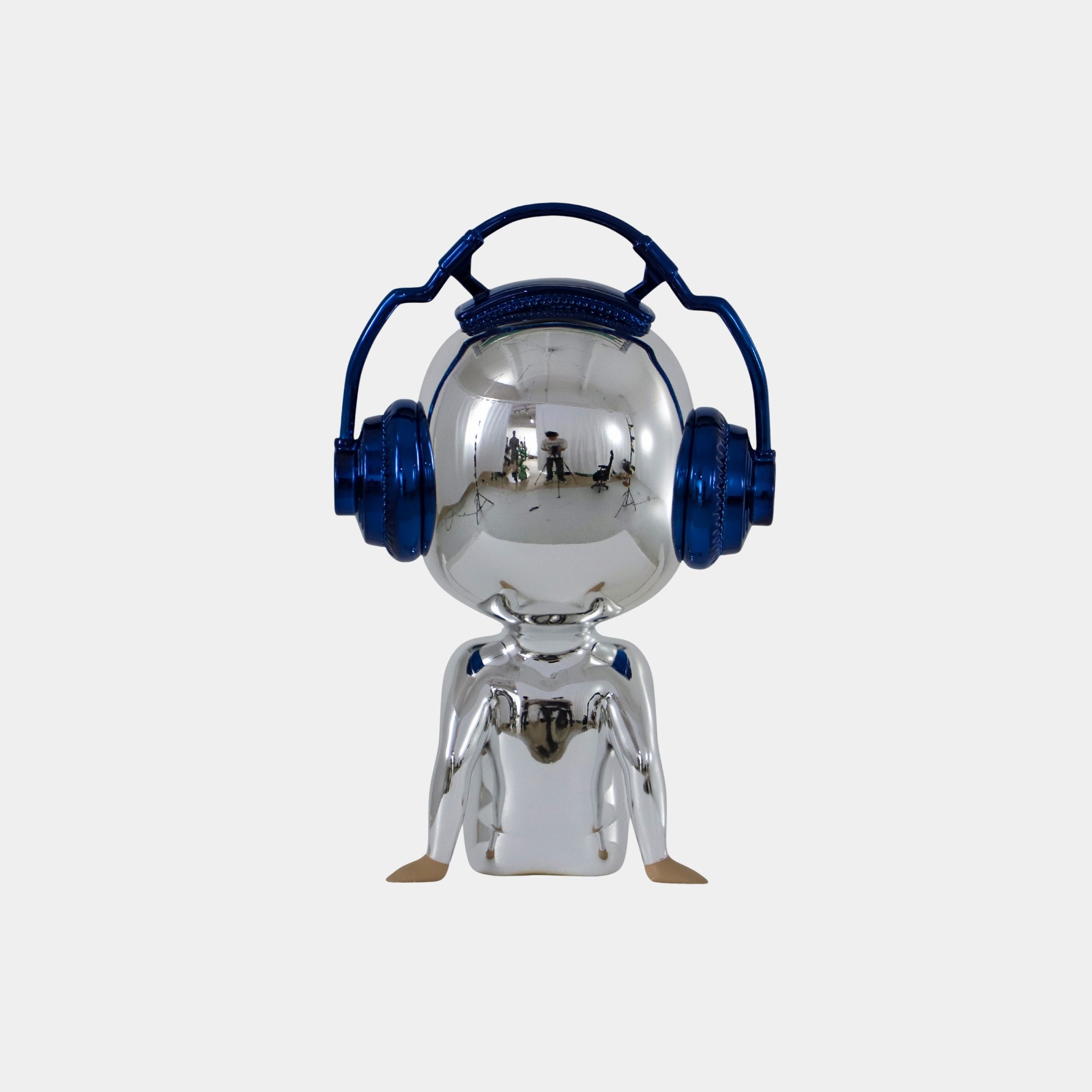The Midnight Chrome Alien Beats Figure - 55cm by Giant Sculptures features a reflective chrome finish, large round head, mirrored visor, and oversized metallic blue headphones, standing out against a plain light gray background.