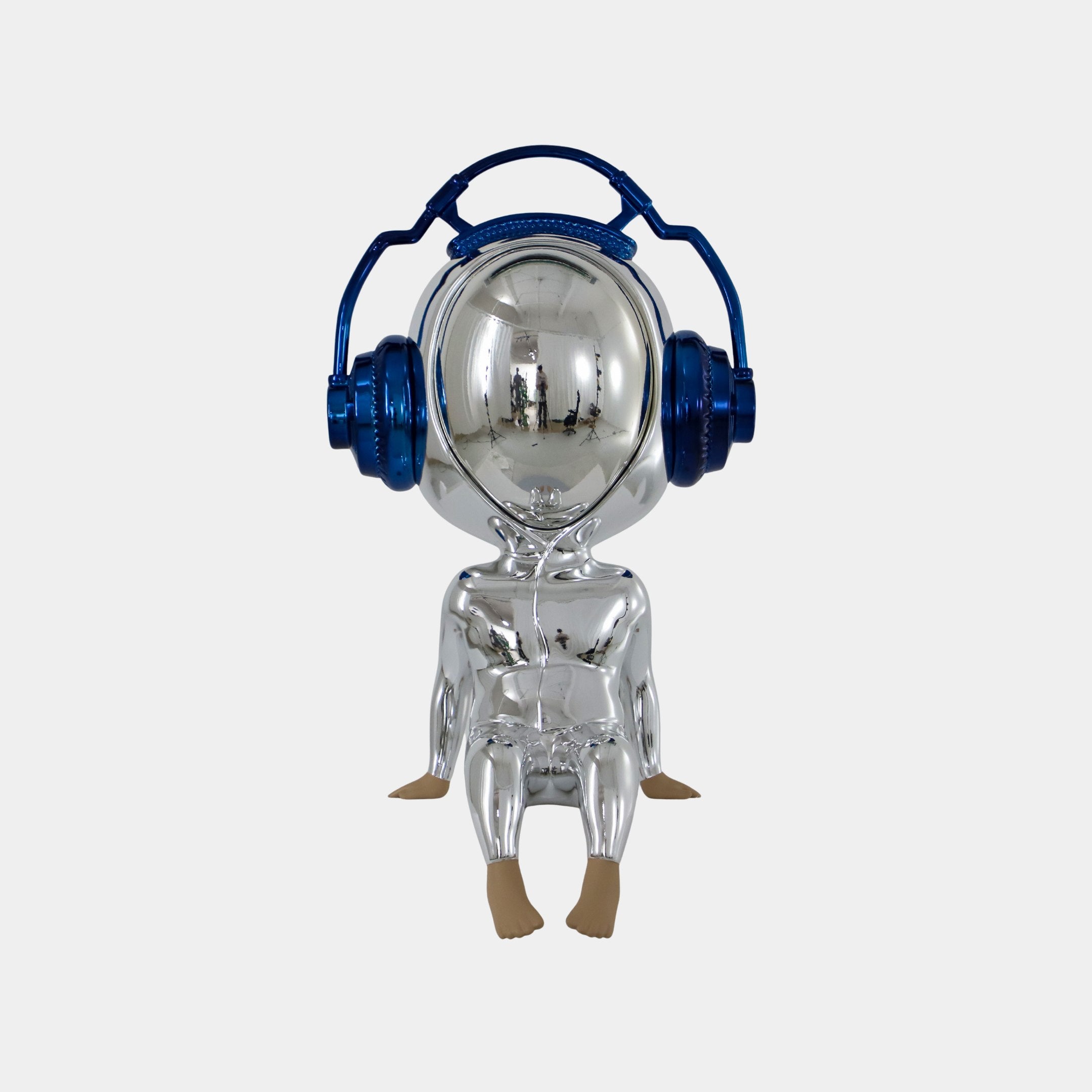 The Midnight Chrome Alien Beats Figure (55cm) by Giant Sculptures features a shiny silver alien with a mirrored helmet visor, oversized blue headphones, and beige feet and hands, seated with legs outstretched on a plain white background.