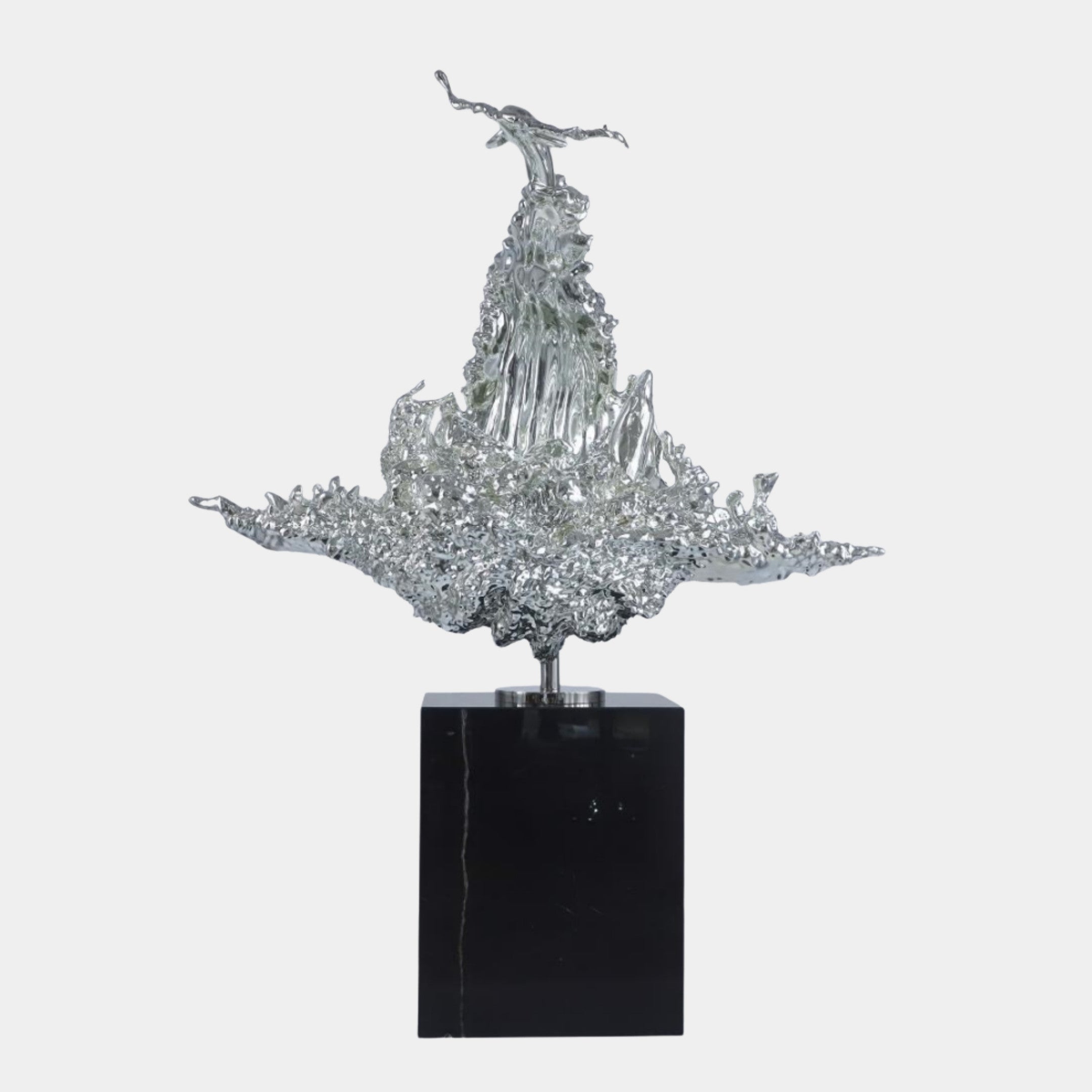 Silver Abstract Ice Crystal Burst Sculpture by Giant Sculptures, a chrome-finished 3D-printed resin splash form on a tall black marble plinth.