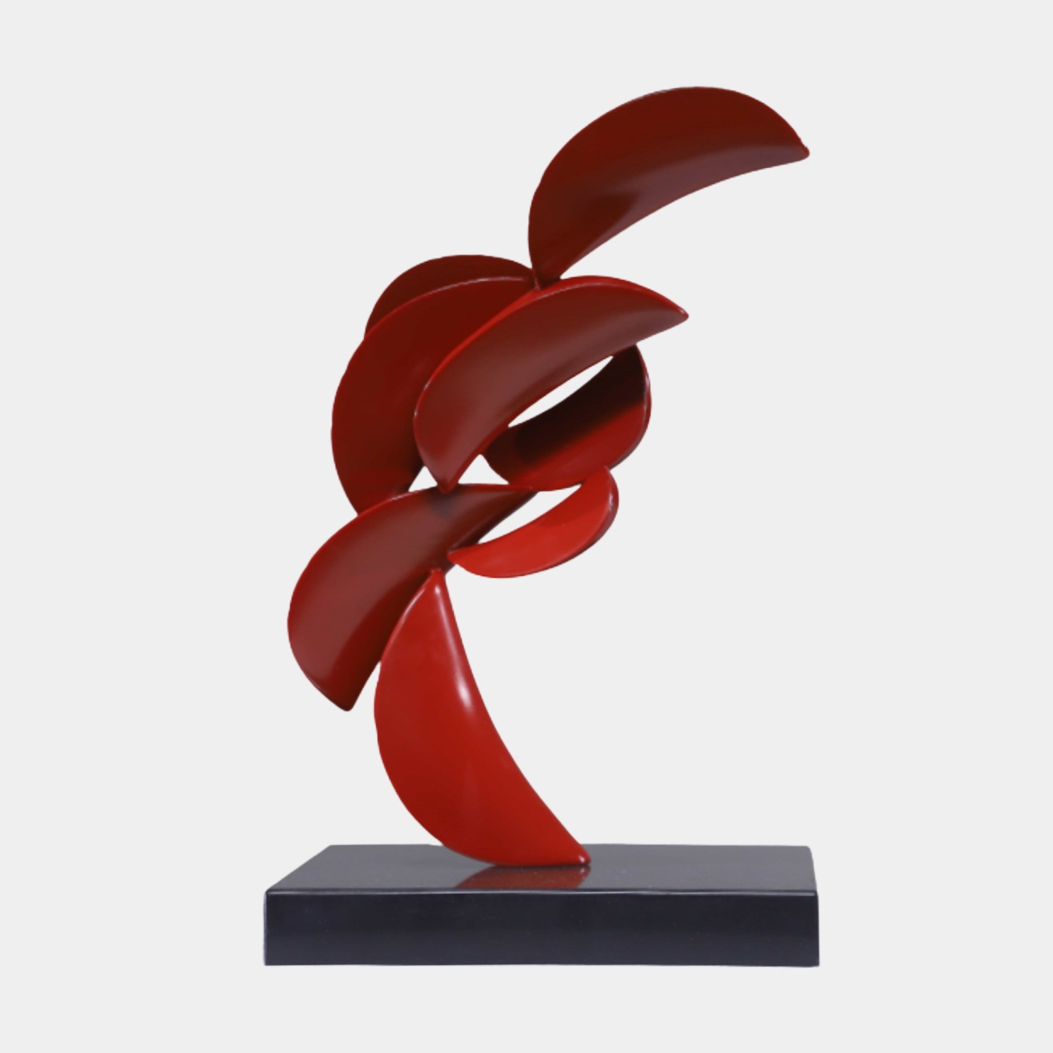 Giant Sculptures Red Abstract Flowing Ribbon Sculpture in glossy red 3D-printed resin with twisting blade-like curves, set on a black marble base.