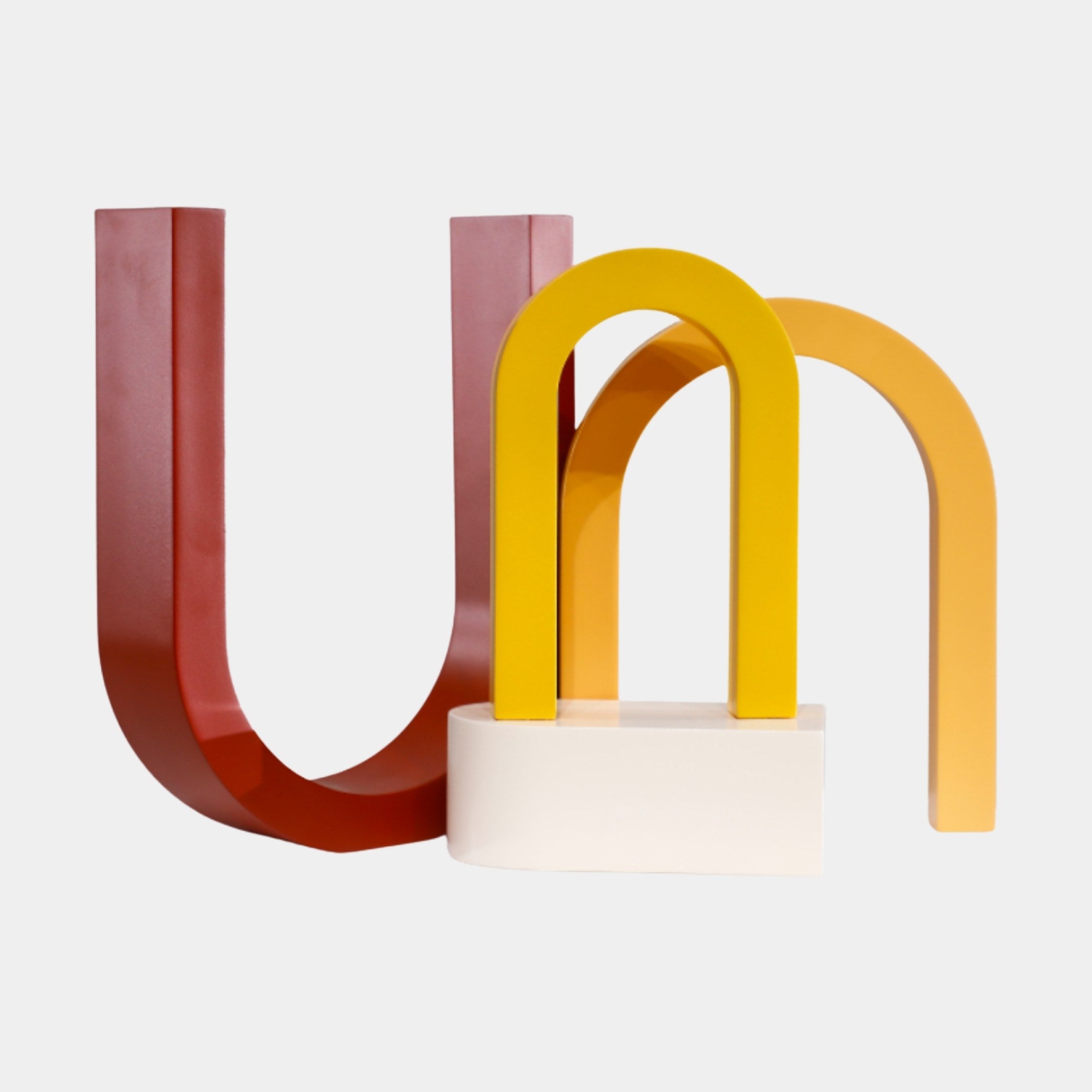 Giant Sculptures Multi-Colour Abstract Letter Forms Sculpture in glossy red, yellow, and orange 3D-printed resin on a cream base, against a plain white background.