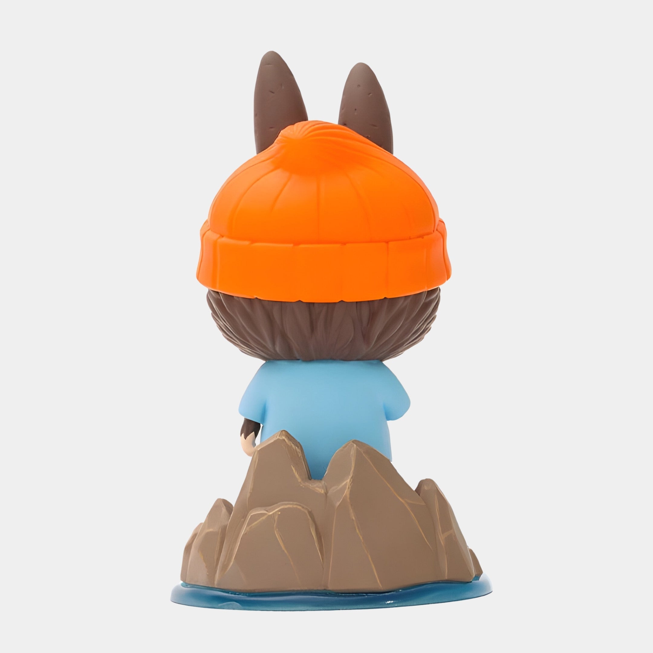 The Submarine Explorer Labubu Sculpture - 100cm by Giant Sculptures features Labubu from behind, in an orange beanie with ears, light blue shirt, and standing on a rocky base surrounded by blue water—a playful tribute to fibreglass-inspired art.
