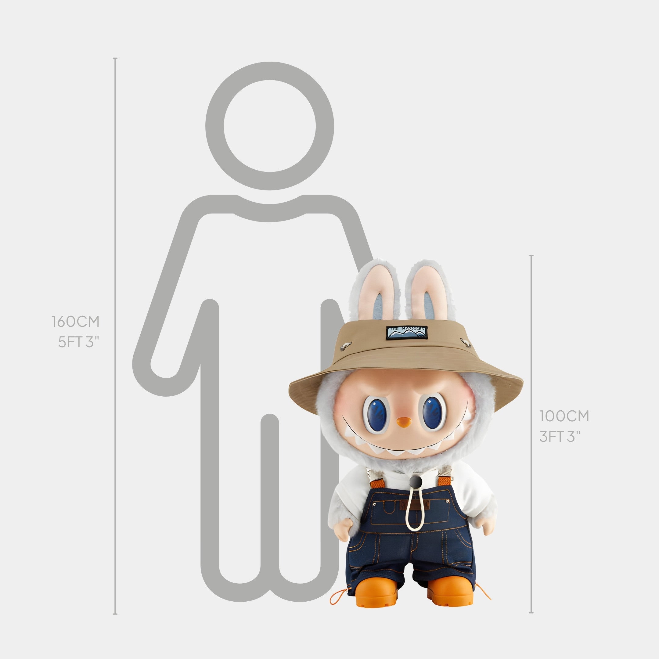 The Monster Fall In Wild Labubu Sculpture - 100cm by Giant Sculptures, dressed in a hat, bunny hood, and overalls, radiates expedition energy beside a 160 cm human outline—perfect for creative interiors.