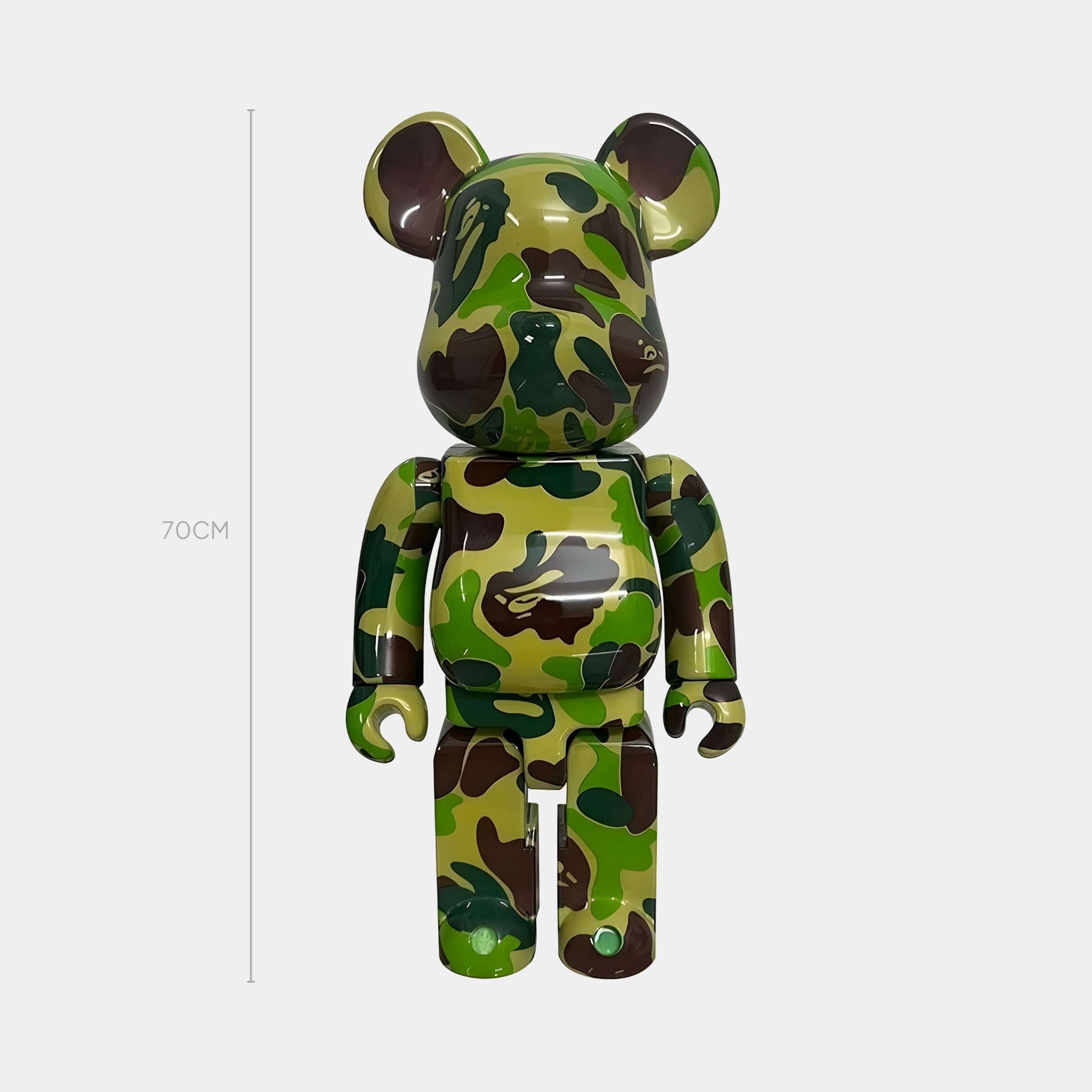 The Forest Drift Bear Sculpture - 70cm by Giant Sculptures features green, brown, and black camouflage resin and stands upright beside a height line on a plain light gray background.